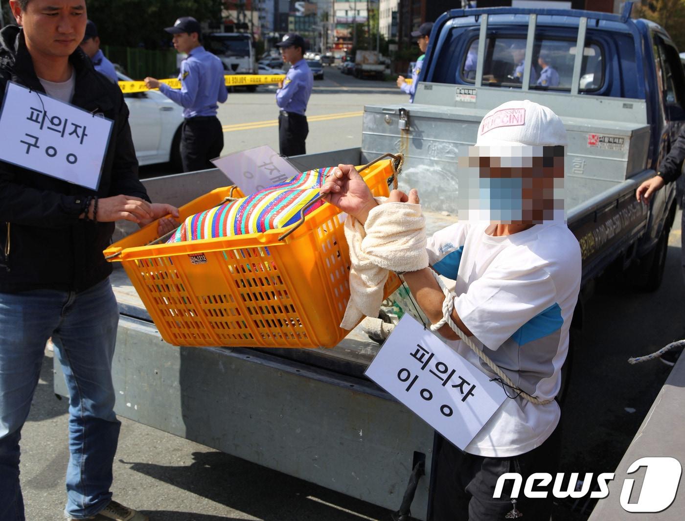 부산항 제2부두에서 이불에 싸인 채 시신이 떠오른 사건과 관련해 3일 오전 부산 남구 문현동 범일교에서 살해 피의자 공범 이모씨&#40;45&#41;가 범행 당시 피해자 김모씨&#40;56·여&#41;의 시신을 노란 바구니에 담아 다리 밑으로 던지는 장면을 재연하고 있다.&#40;부산해양경찰서 제공&#41; ⓒ News1