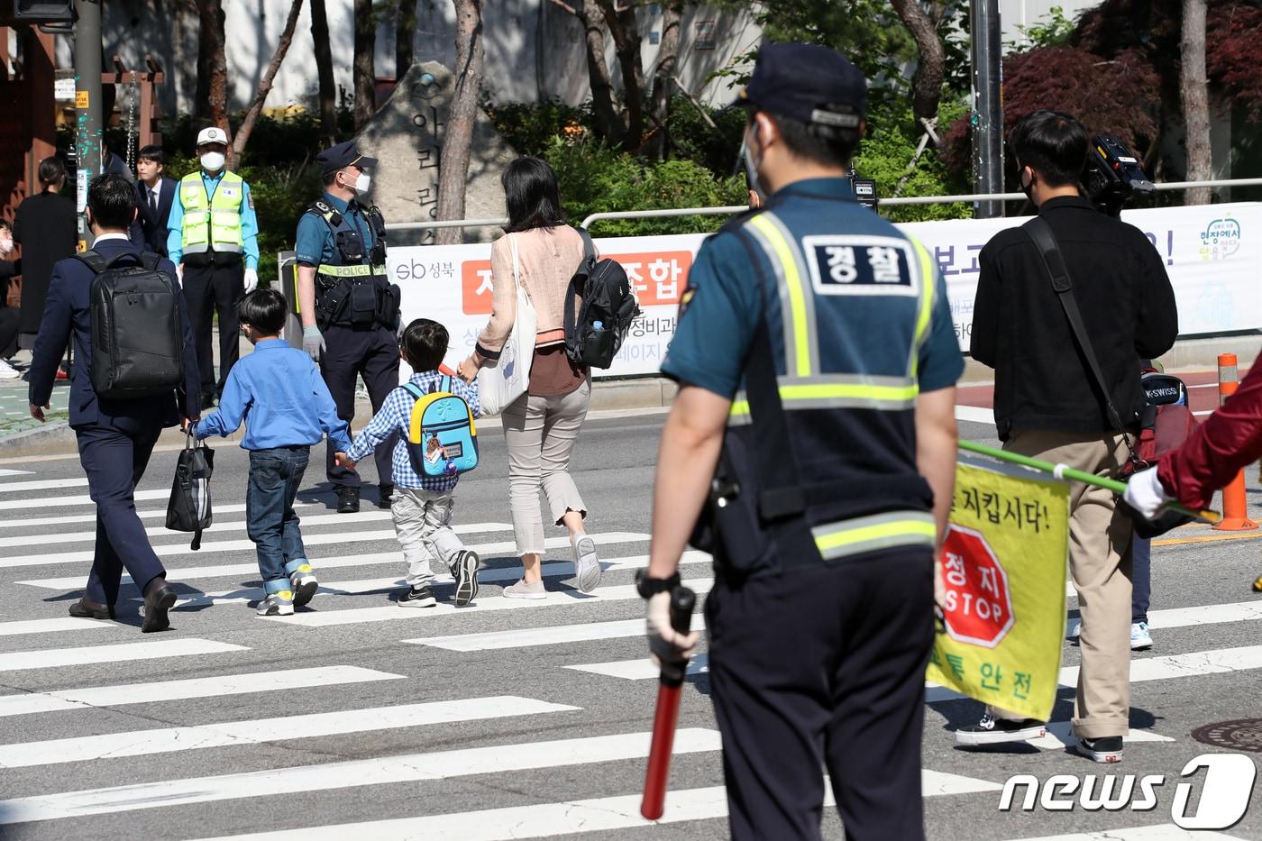 고등학교 2학년과 중학교 3학년, 초등학교 1∼2학년, 유치원생 등교 개학이 시작된 27일 오전 서울 성북구 정덕초등학교 인근에서 경찰과 교통안전 자원봉사원들이 등교 지도를 하고 있다. 2020.5.27/뉴스1 ⓒ News1 이승배 기자