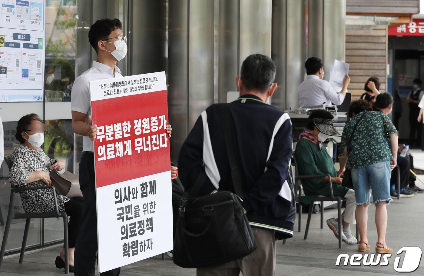 1일 서울 종로구 서울대병원 본관 앞에서 한 전공의가 정부의 의료정책에 반대하는 피켓을 들고 있다./뉴스1 ⓒ News1 박지혜 기자