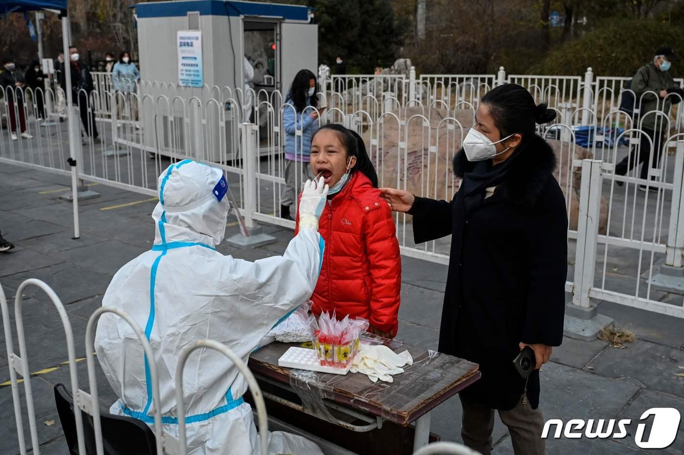 지난 11월23일 중국 베이징의 한 지하철역 앞에서 주민들이 거리의 방역 요원들로부터 코로나19 검사를 받고 있다. ⓒ AFP=뉴스1 ⓒ News1 강민경 기자