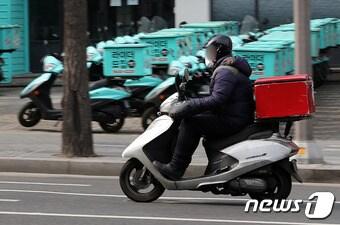 서울 강남구 배민라이더스 남부센터에 세워진 배달용 오토바이 앞으로 한 배달 노동자가 지나가고 있다. ⓒ News1 박세연 기자