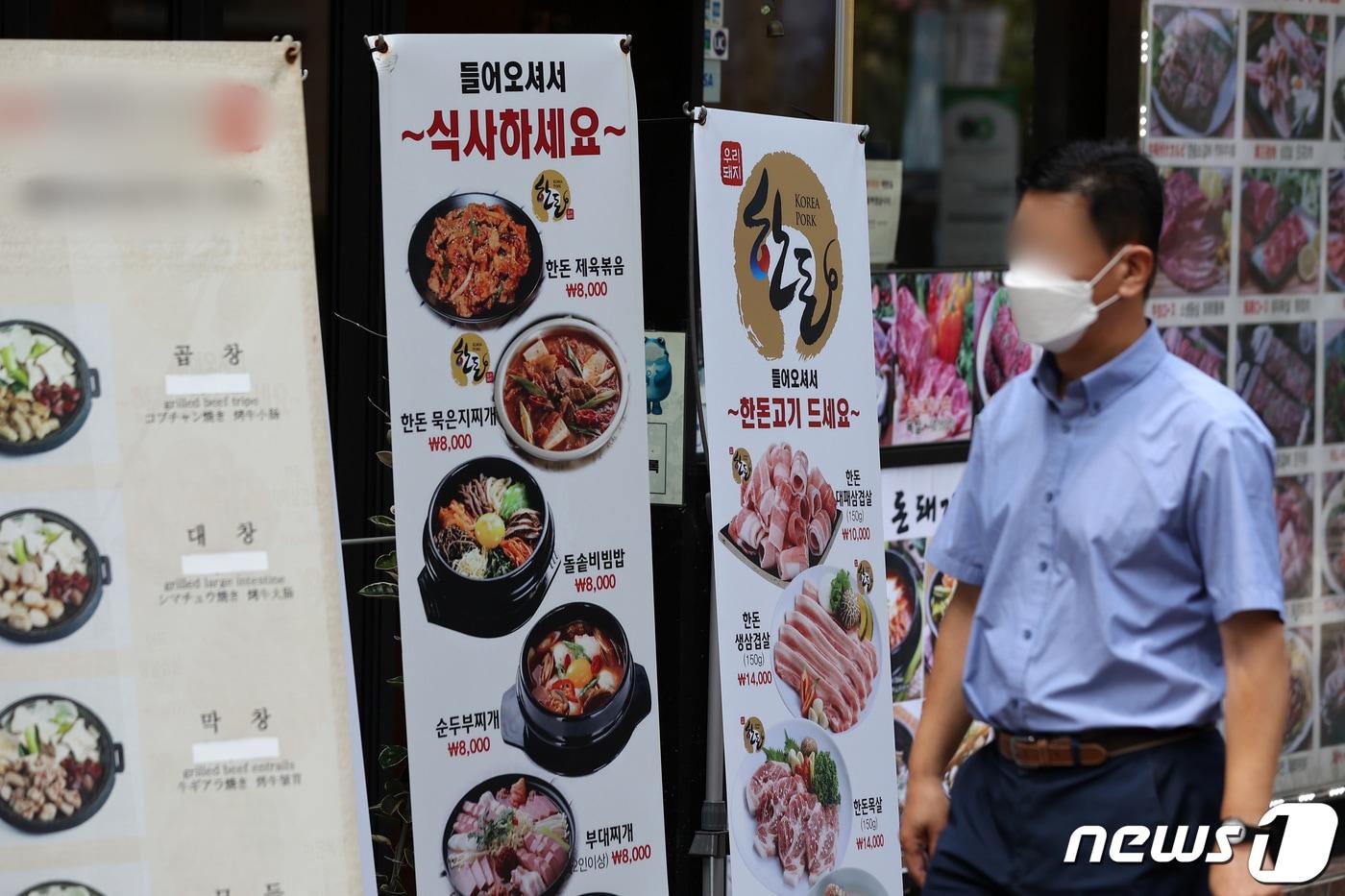  25일 서울 시내 한 거리에서 시민들이 마스크를 착용한 채 식당 메뉴 알림판 앞을 지나고 있다. 2022.7.25/뉴스1 ⓒ News1 조태형 기자