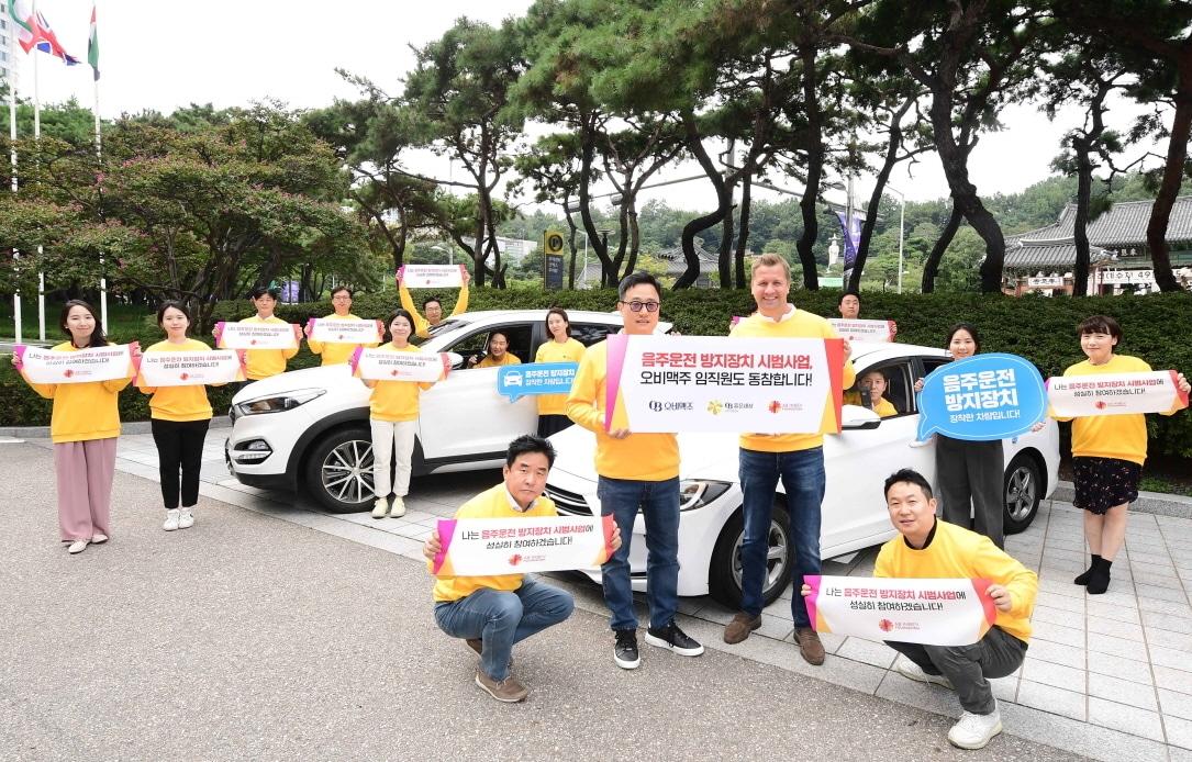 오비맥주 임직원들이 이달 14일 강남구 삼성동 본사 앞에서 음주운전방지장치 설치 후 기념 사진을 찍고 있다. 맨 앞줄 왼쪽부터 구자범 오비맥주 법무정책홍보 부사장, 배하준 오비맥주 대표.&#40;오비맥주 제공&#41;