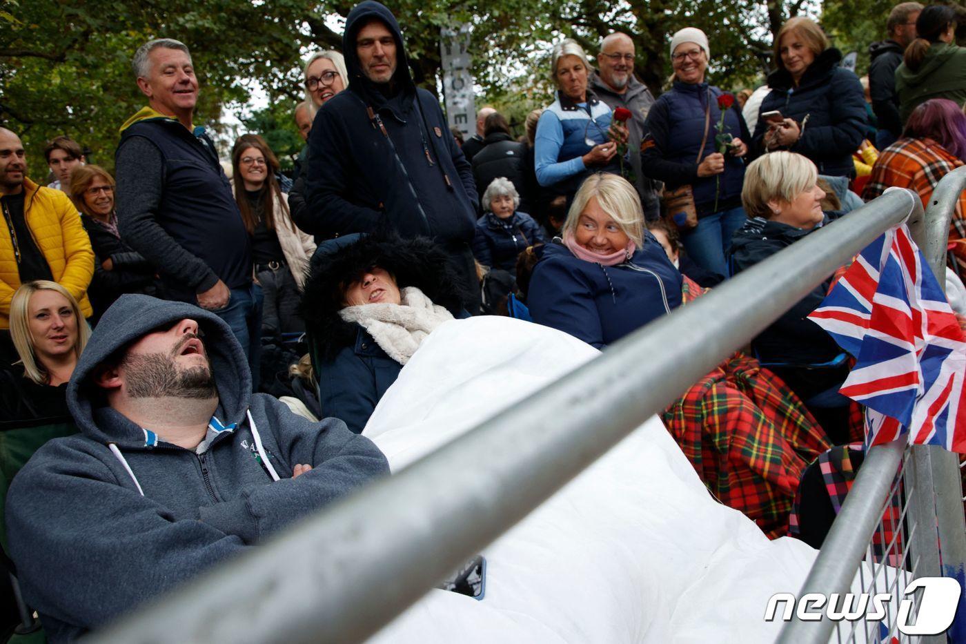 19일&#40;현지시간&#41; 엘리자베스 2세 영국 여왕의 운구 행렬을 보기 위해 이른 아침에 집을 나선 국민들이 펜스 뒤에서 잠을 청하고 있다. 22.09.19 ⓒ AFP=뉴스1 ⓒ News1 김예슬 기자