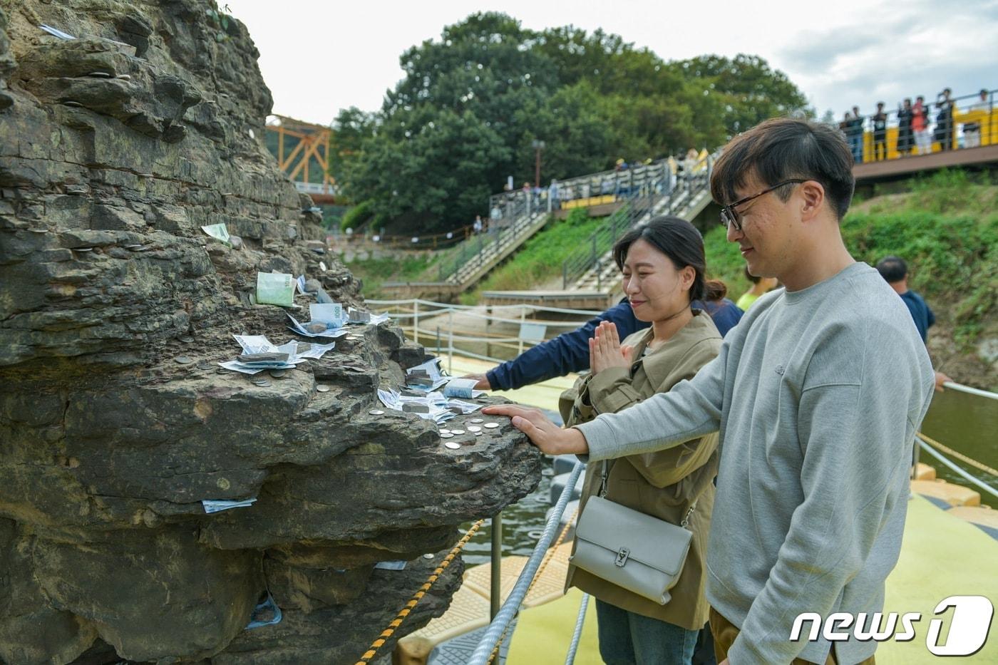  경남 의령군이 6일부터 9일까지 진행한 리치리치페스티벌 기간 가족 나들이객이 솥바위를 만지며 소원을 빌고 있다.&#40;의령군 제공&#41;