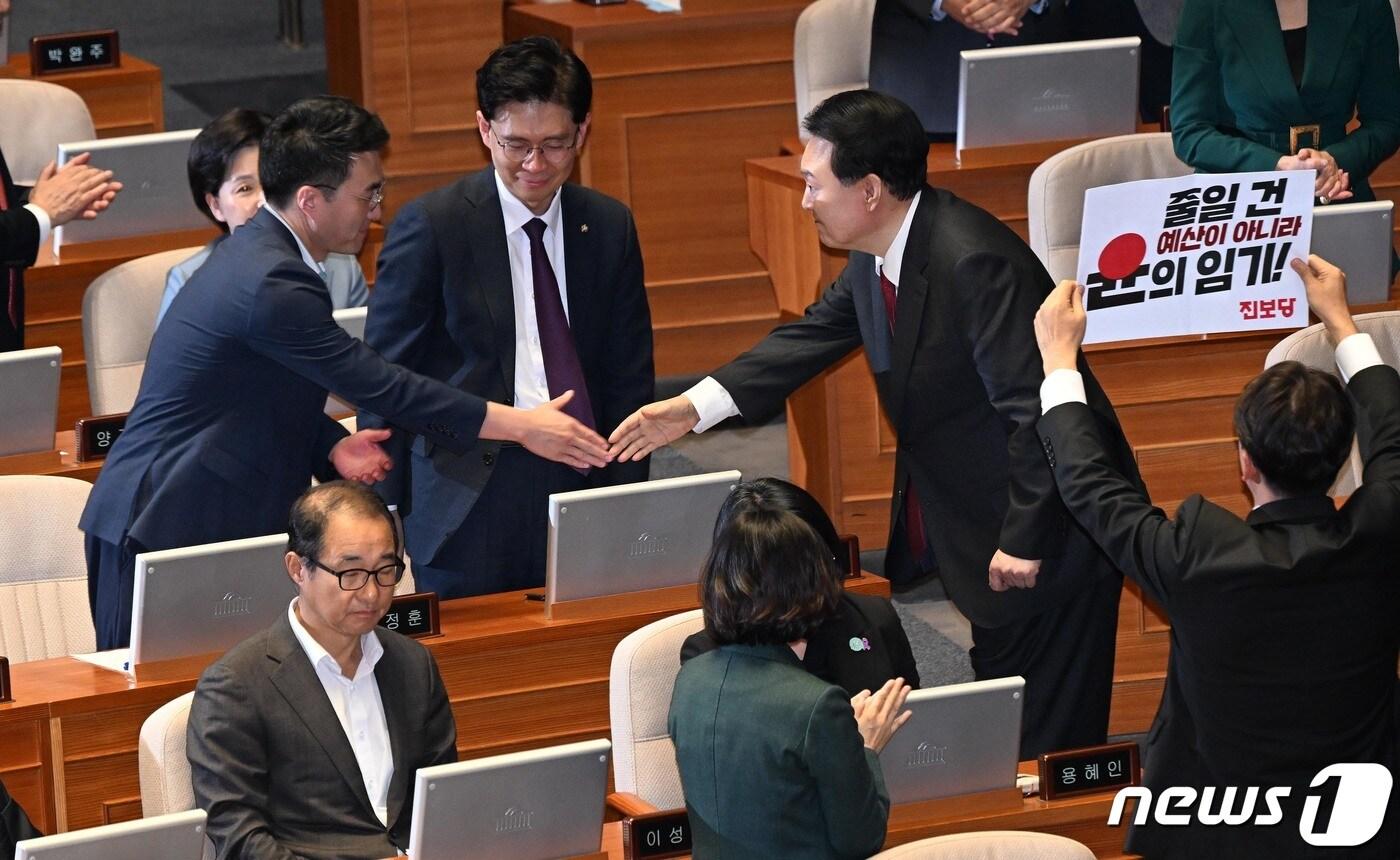 윤석열 대통령이 31일 서울 여의도 국회에서 시정연설을 마친 뒤 김남국 무소속 의원과 악수하고 있다. 오른쪽은 피켓을 들고 항의하고 있는 진보당 강성희 의원. &#40;공동취재&#41; 2023.10.31/뉴스1 ⓒ News1 송원영 기자