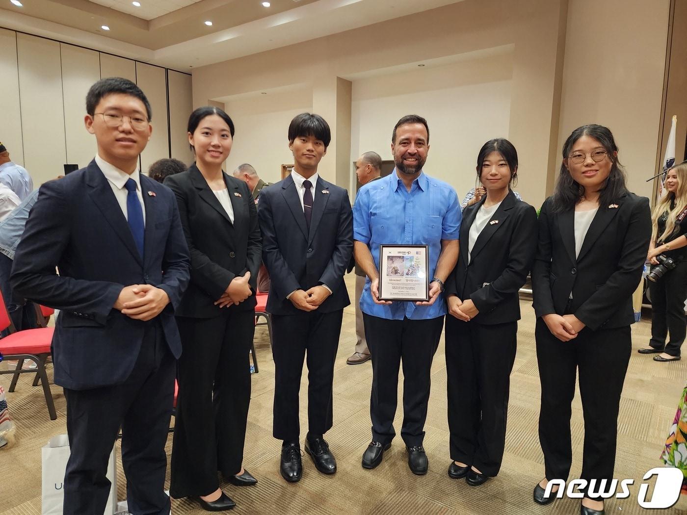 국제청소년연합&#40;IYF&#41; 산하 굿뉴스코 해외봉사단은 11일&#40;현지시간&#41; 푸에르토리코 카보로호시의 컨벤션센터에서 열린 재향군인의 날 행사를 마친 뒤 한국전 참전용사들에 대한 감사의 뜻을 담은 삽화를 전달한 뒤 오말 마레로 국무부 장관&#40;가운데&#41;과 기념 촬영을 하고 있다. 왼쪽부터 추은상, 박수연, 김경언, 라령, 정은영 단원. 사진은 국제청소년연합 제공.