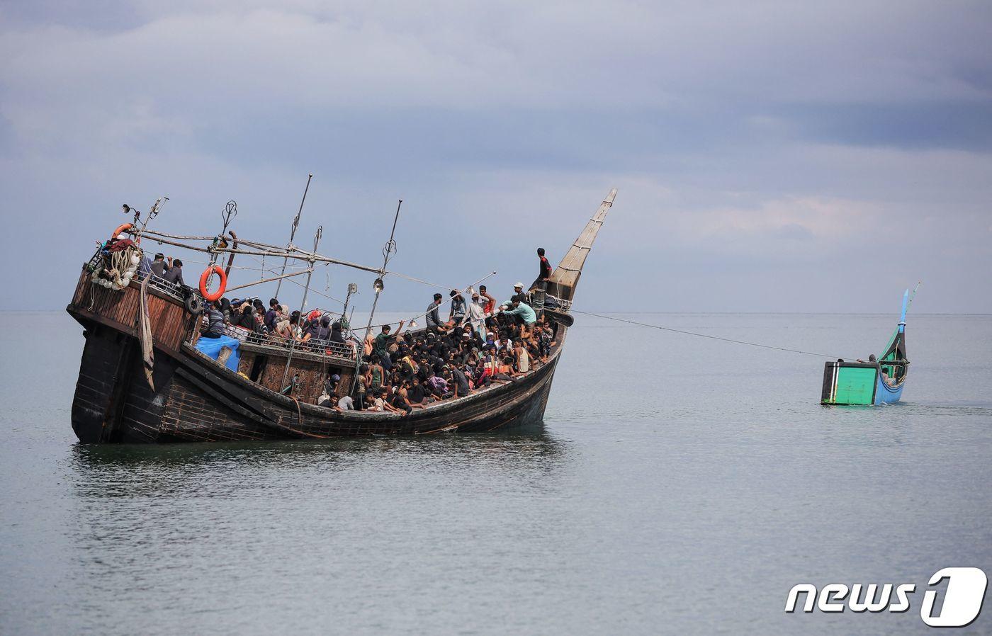 16일&#40;현지시간&#41; 인도네시아 아체주의 해변에 새로 도착한 로힝야 족 난민들이 음식과 물을 제공 받은 뒤 상륙은 허락 받지 못하자 어선이 난민의 목선을 예인하고 있다. 2023.11.16 ⓒ AFP=뉴스1 ⓒ News1 우동명 기자