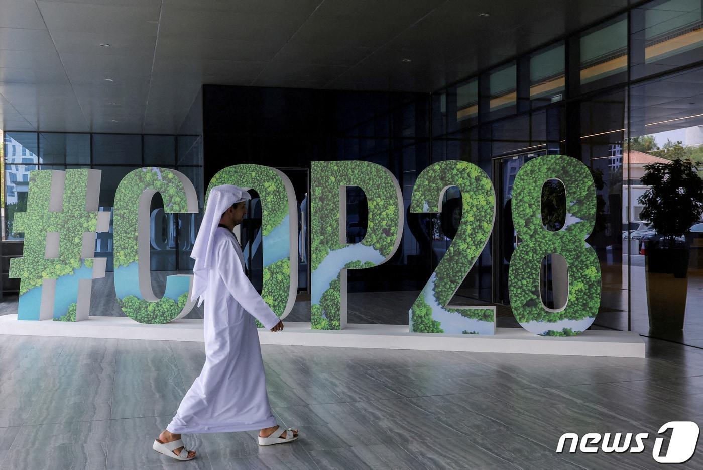 제28차 유엔기후변화협약 당사국총회&#40;COP28&#41;가 열리는 아랍에미리트&#40;UAE&#41; 아부다비에서 행인이 COP28을 홍보하는 게시물 앞으로 지나가고 있다. 2023.10.01/ ⓒ 로이터=뉴스1 ⓒ News1 박재하 기자