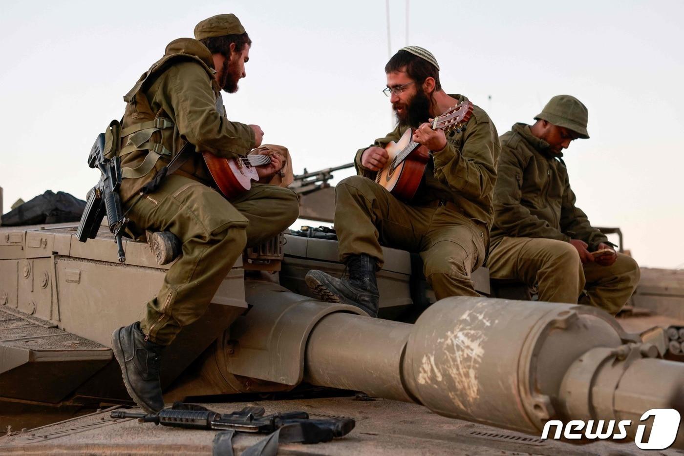 이스라엘군 병사들이 29일&#40;현지시간&#41; 가자지구와 이스라엘의 남부 접경지역에서 탱크에 올라가 기타를 연주하고 있다. 2023.11.30 ⓒ AFP=뉴스1 ⓒ News1 정지윤 기자