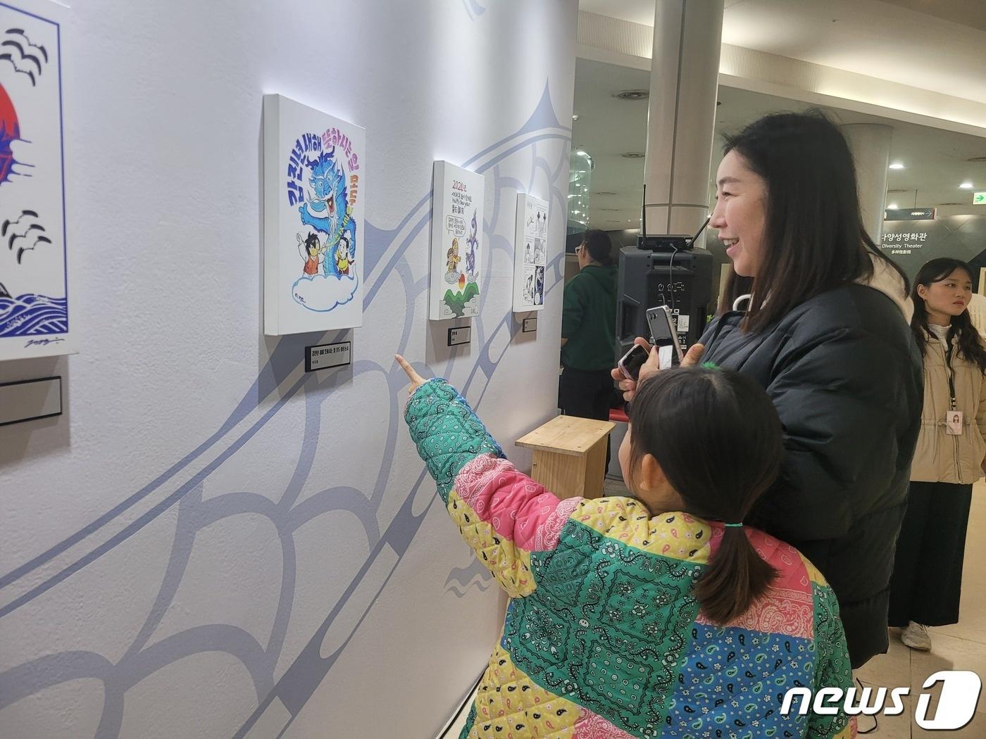 12일 경기 부천시 한국만화박물관에서 열린 ‘행복하세龍&#40;용&#41;’ 새해카툰전에 방문한 함소연씨가 딸 용태은양과 함께 작품을 관람하고 있다./ 뉴스1 ⓒ News1 이시명기자