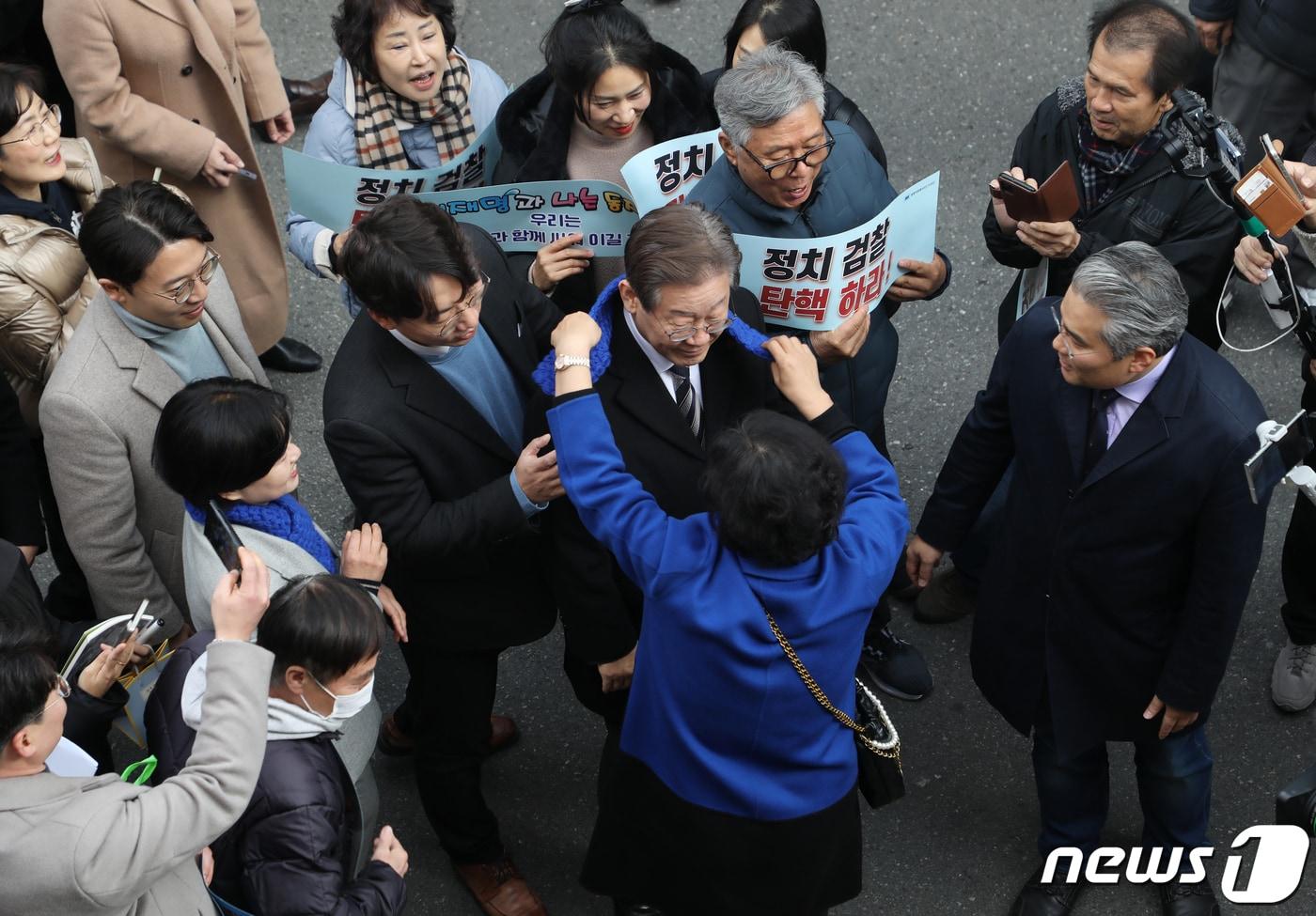 이재명 더불어민주당 대표가 13일 오후 부산 수영구 한 카페에서 열린 부산지역 전세사기 피해자 현장 간담회에 참석하며 지지자로부터 파란 목도리를 선물받고 있다. 2023.12.13/뉴스1 ⓒ News1 윤일지 기자