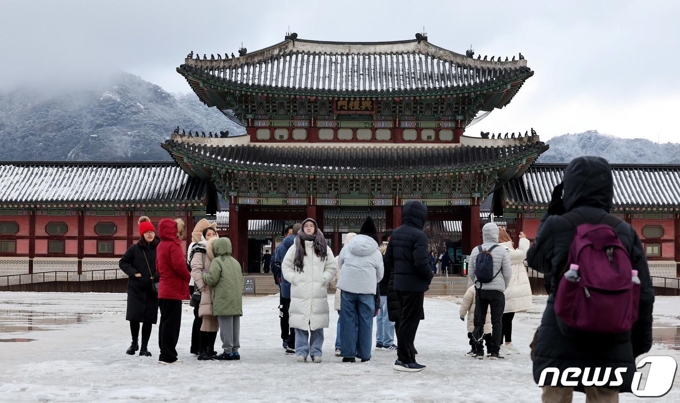 아침까지 약한 눈비가 이어진 31일 오전 서울 종로구 경복궁을 찾은 관광객이 설경을 바라보고 있다. 기상청은 오늘 오전 비가 그친 뒤 흐린 날씨가 이어져 해넘이를 보기 어렵고 새해 해맞이는 볼 수 있을 것이라고 예보했다. 2023.12.31/뉴스1 ⓒ News1 장수영 기자