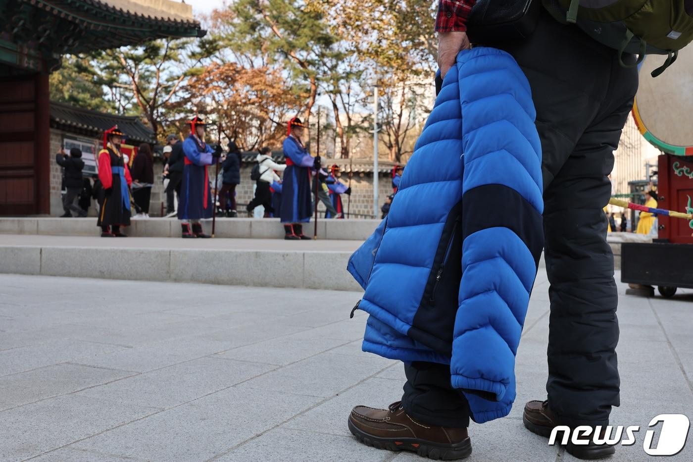 낮 기온이 14도까지 올라간 5일 오후 덕수궁 앞에서 한 시민이 겉옷을 벗은 채 수문장 교대 의식을 관람하고 있다. 2023.12.5/뉴스1 ⓒ News1 신웅수 기자