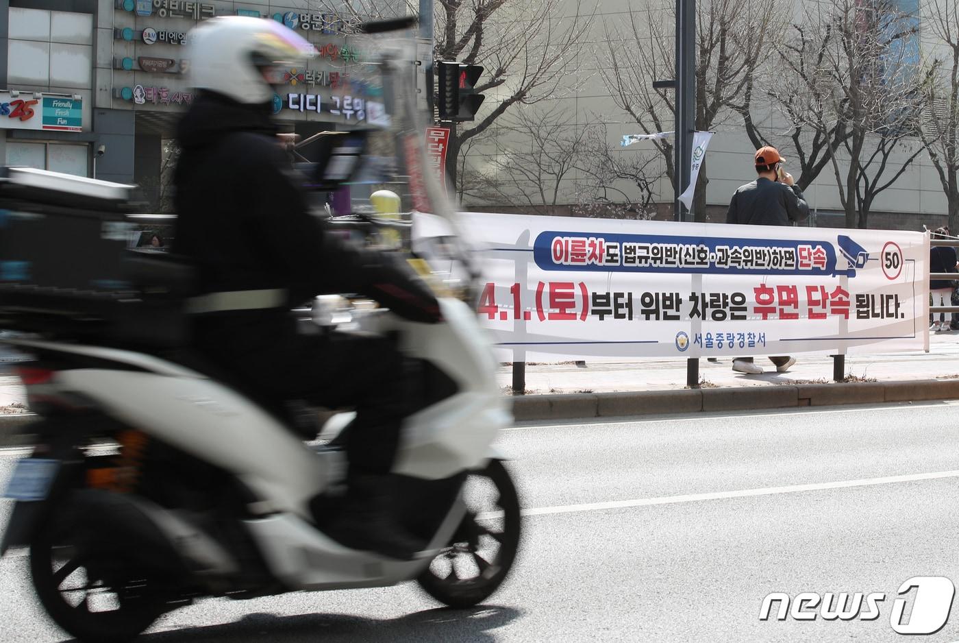 서울 중랑구 망우로 버스중앙차로에 설치된 후면 단속 안내 현수막 앞으로 오토바이가 지나가고 있다.. 2023.3.30/뉴스1 ⓒ News1 박정호 기자