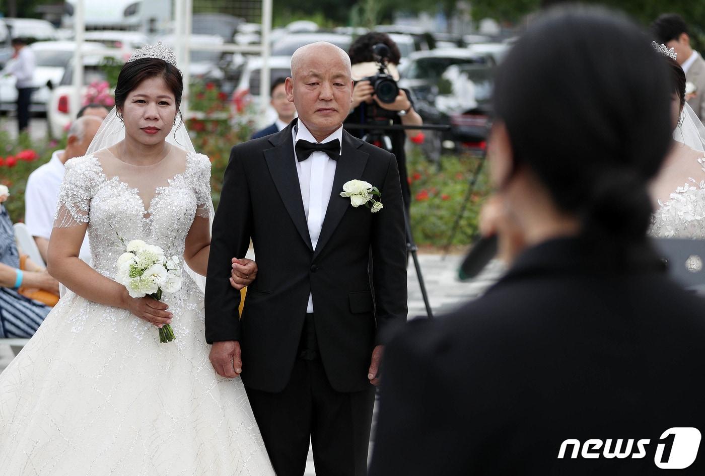 신랑 김모씨와 신부가 지난 6월 서울 광나루한강공원 장미원에서 결혼식을 하고 있다. 이날 결혼식은 서울시 한강사업본부가 KB증권과 사회공헌사업으로 사회취약층을 대상으로 자치구 및 사회복지기관으로부터 추천을 받아 장애인·다문화, 북한이탈주민·다문화 가정 두쌍을 선정해 진행한 합동 결혼식이다. 2023.6.11/뉴스1 ⓒ News1 박세연 기자