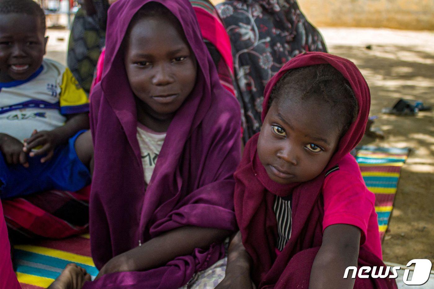 수단 난민 캠프에서 두 소녀가 나란히 앉아 있다. ⓒ AFP=뉴스1