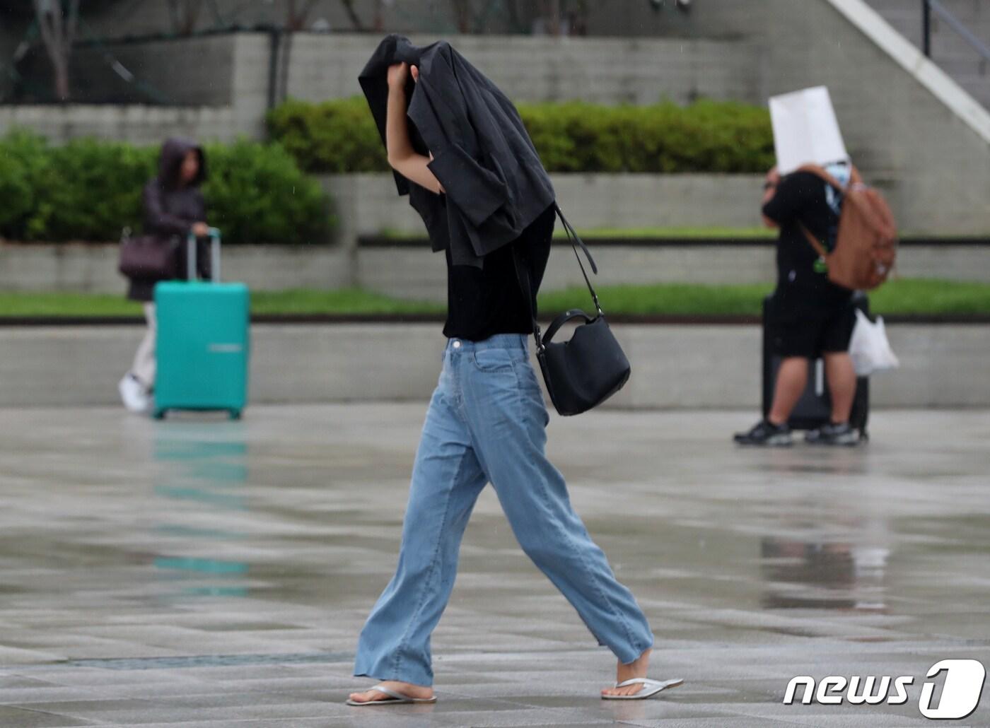 부산지역에 장맛비가 내리는 7일 오후 부산역 광장에서 한 시민이 겉옷으로 비를 피하고 있다. 2023.7.7/뉴스1 ⓒ News1 윤일지 기자