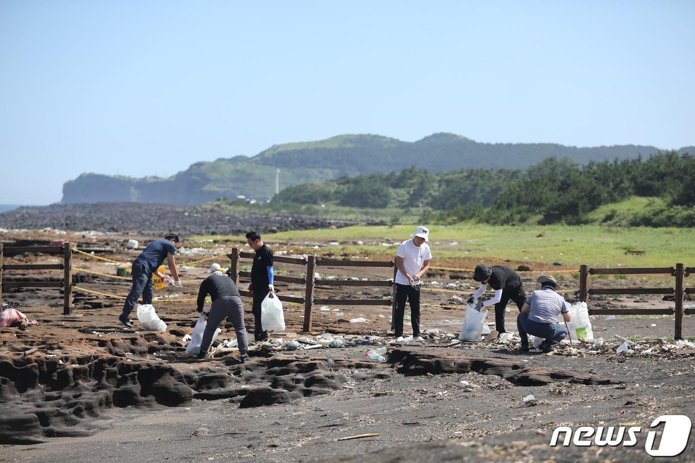 제주신화월드 직원들이 서귀포시 안덕면 사계해안가에서 해양폐기물을 줍고 있다