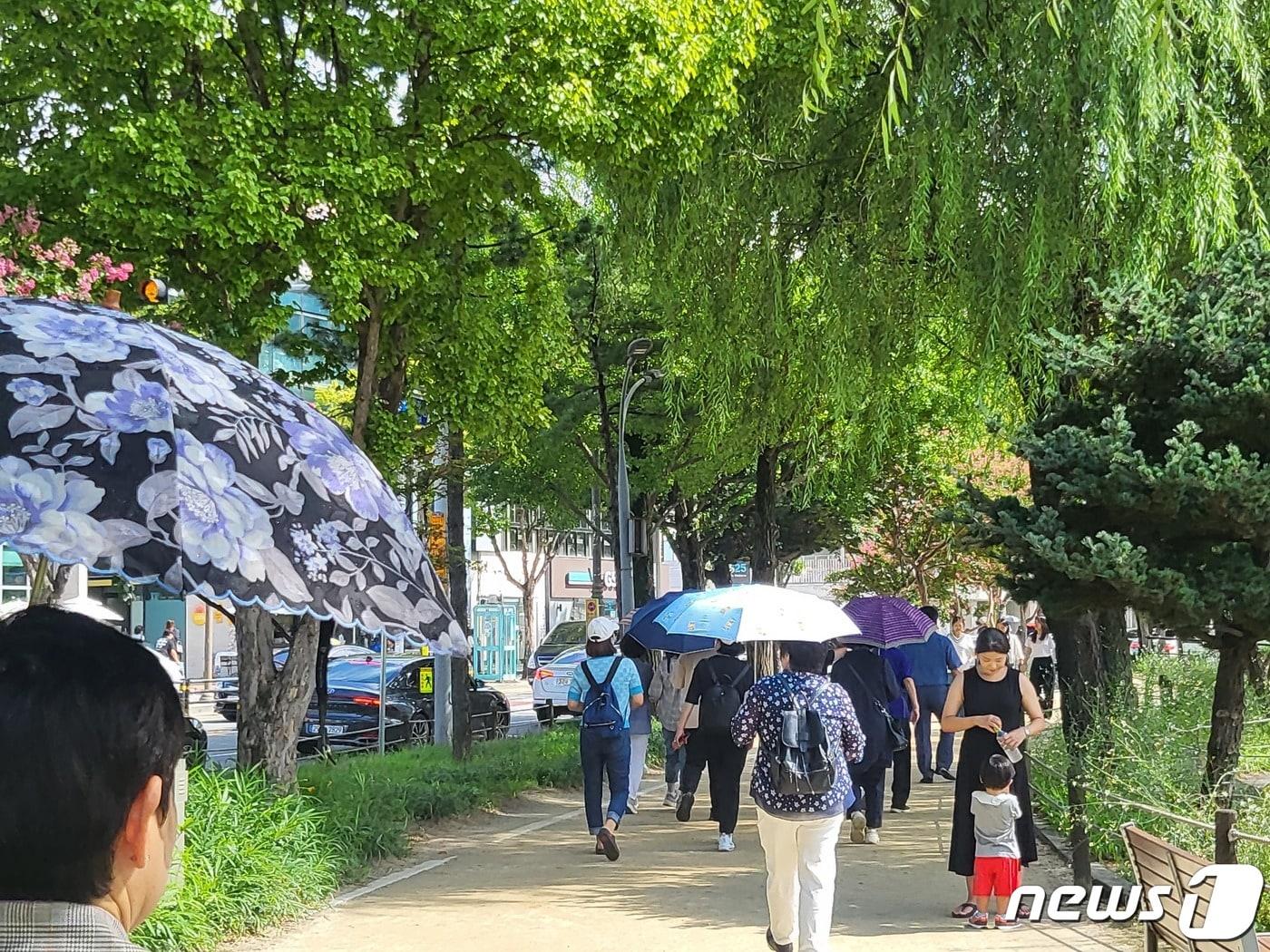 3일 오후 대구 대표관광지 수성못에 나온 시민들이 그늘을 만들고자 우산을 쓰며 이동하고 있다.2023.9.3/뉴스1 ⓒ News1 이성덕 기자