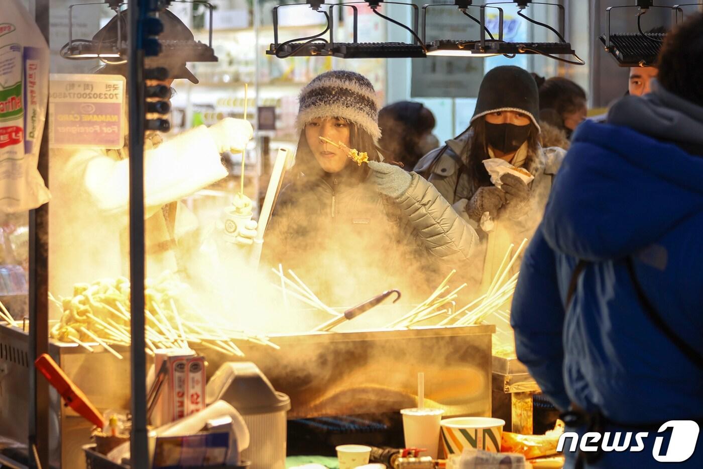 전국에 한파가 몰아닥친 지 23일 저녁 서울 중구 명동거리의 포장마차에서 외국인 관광객들이 뜨거운 김이 피어오르는 어묵을 맛보고 있다. 2024.1.23/뉴스1 ⓒ News1 민경석 기자