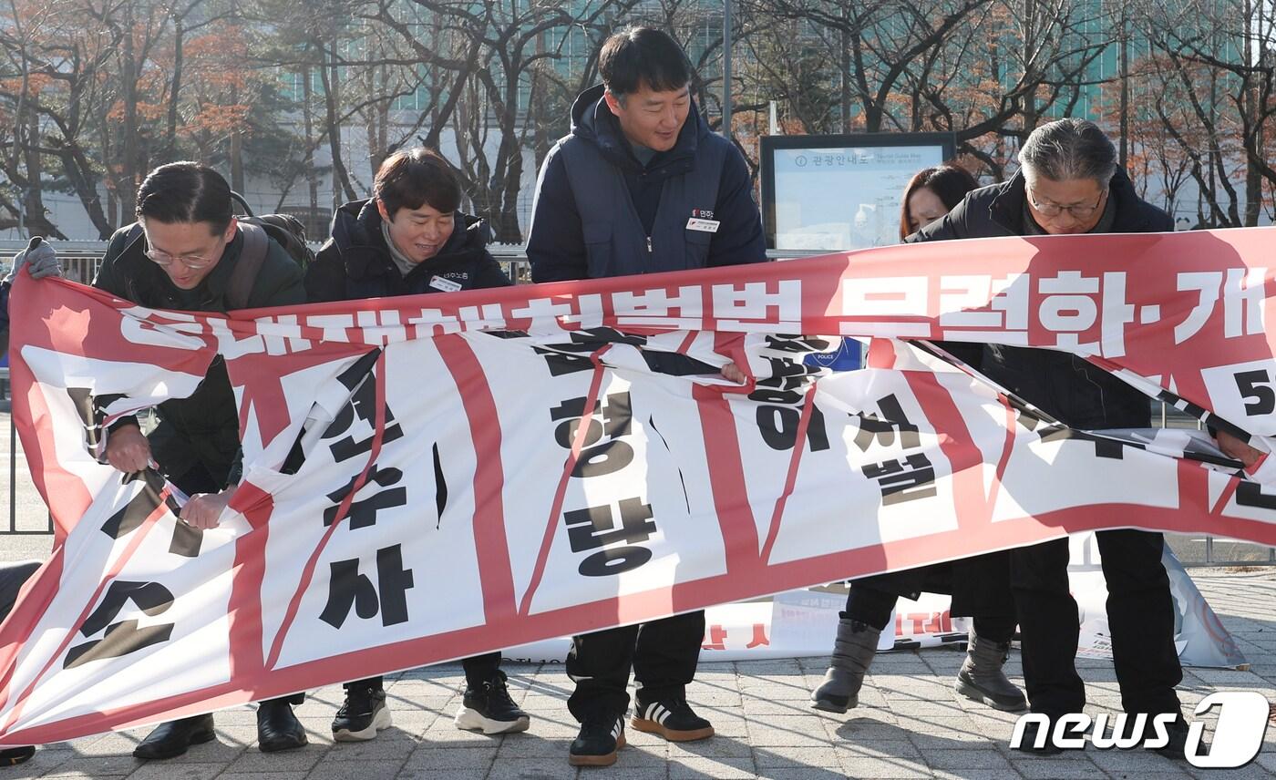 민주노총 관계자들이 26일 오전 서울 용산 전쟁기념관 앞에서 열린 중대재해처벌법 시행 2년 기자회견에서 중대재해처벌법 개악 시도 중단과 50인 미만 사업장의 적용을 촉구하는 현수막 찢기 퍼포먼스를 하고 있다. 2024.1.26/뉴스1 ⓒ News1 김민지 기자