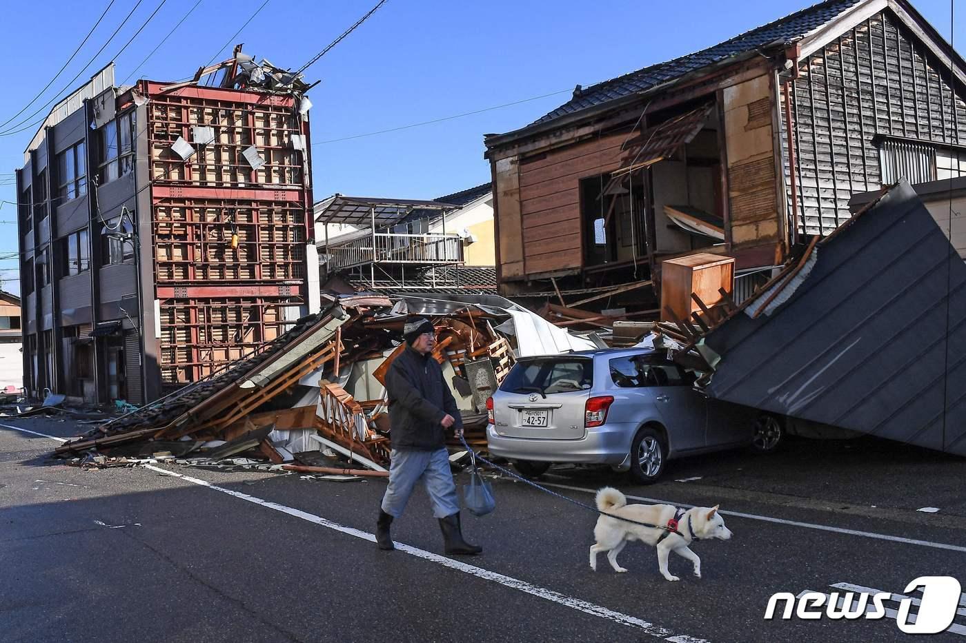 7.6 규모의 강진이 일어난 일본 이시카와현 아나미즈 지역 건물들이 무너져 있는 가운데 4일 한 남성이 개를 산책시키고 있다. 2024.01.04 ⓒ AFP=뉴스1 ⓒ News1 정지윤 기자