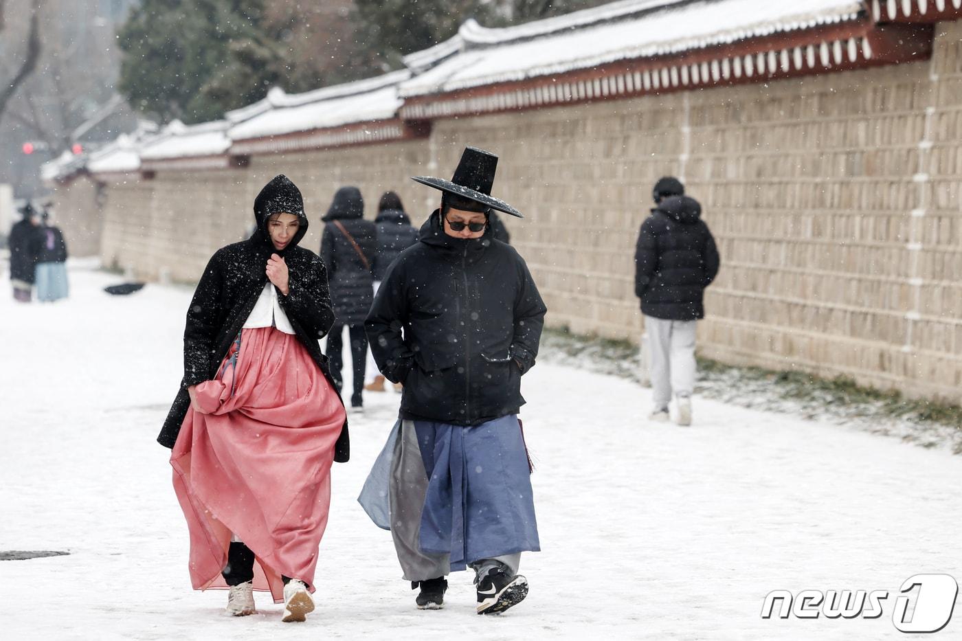 서울을 비롯한 전국에 대설주의보가 발효된 9일 서울 종로구 경복궁 건춘문 앞에서 한복차림 위에 두꺼운 겨울외투를 껴입은 대만인 관광객들이 눈을 맞으며 걸음을 옮기고 있다. 2024.1.9/뉴스1 ⓒ News1 민경석 기자