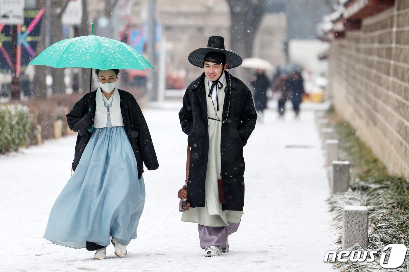 서울을 비롯한 전국에 대설주의보가 발효된 9일 서울 종로구 경복궁 건춘문 앞에서 한복차림 위에 두꺼운 겨울외투를 껴입은 대만인 관광객들이 눈을 맞으며 걸음을 옮기고 있다. 2024.1.9/뉴스1 ⓒ News1 민경석 기자