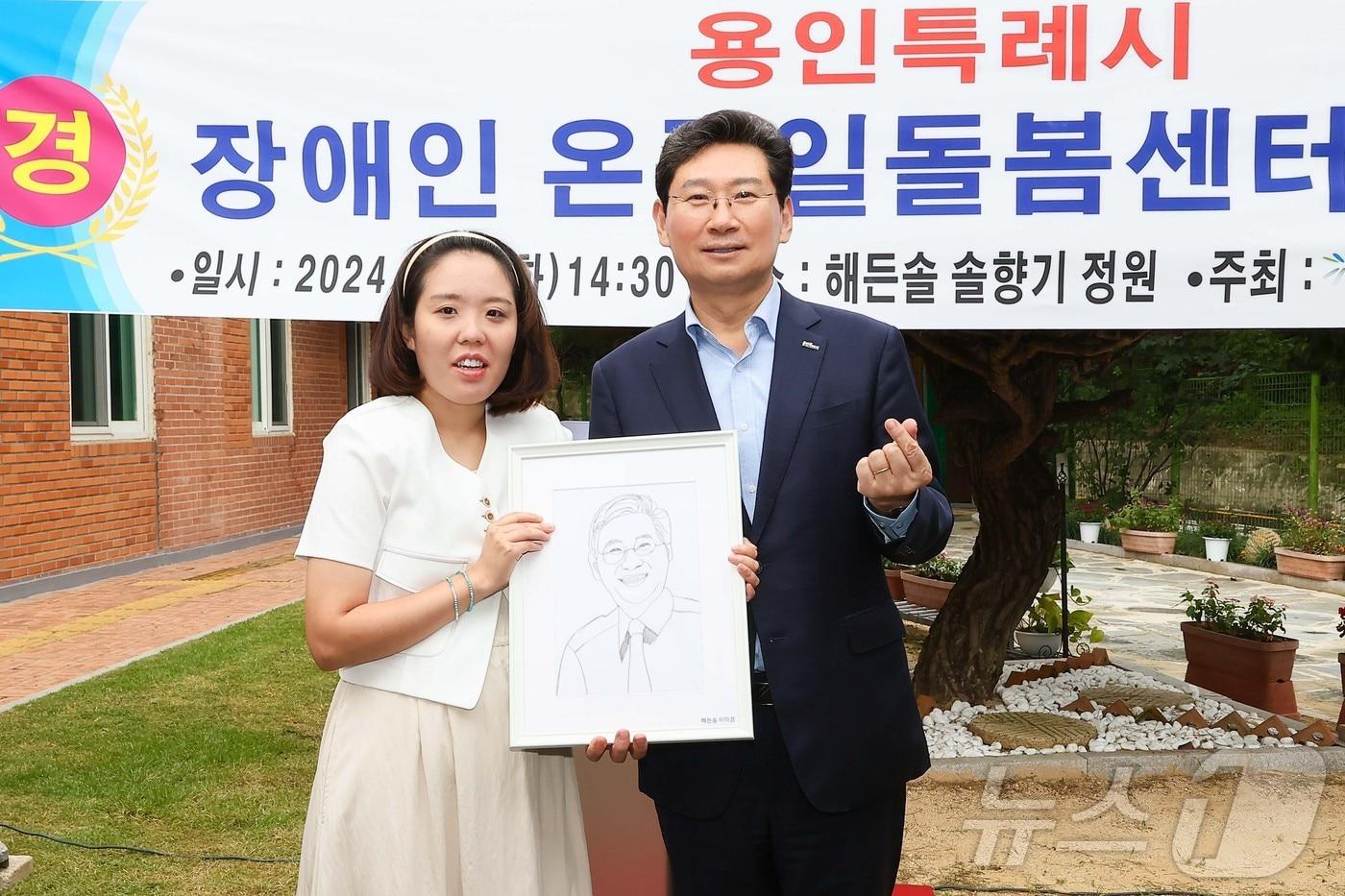 이상일 시장&#40;오른쪽&#41;과 직접 그린 이 시장 캐리커쳐를 선물한 발달장애인 화가 이미경씨&#40;왼쪽&#41;.&#40;용인시 제공&#41;