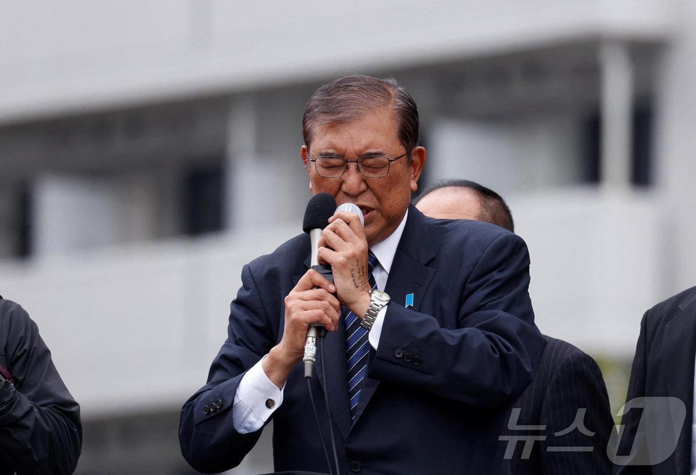 26일 일본 도쿄에서 자민당을 이끄는 이시바 시게루 총리가 마이크에 두 손을 모으고 간절한 표정으로 길거리 연설을 하고 있다. 2024.10.26/ ⓒ 로이터=뉴스1 ⓒ News1 권진영 기자