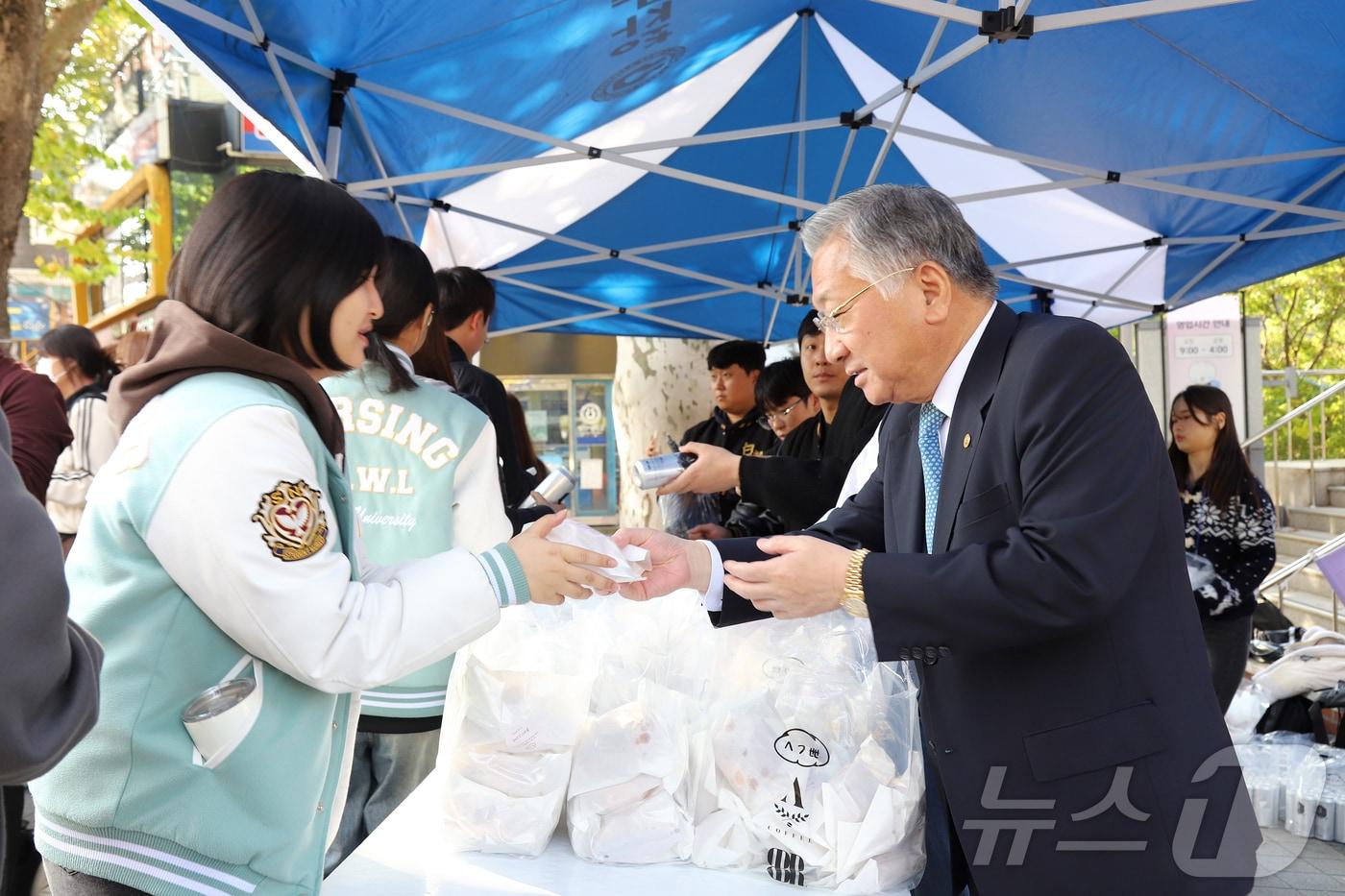 청주대 김윤배 총장&#40;오른쪽&#41;이 30일 중앙도서관 앞 중문에서 총학생회와 단과대학학생회 간부들과 함께 학생들에게 간식을 나눠주고 있다.&#40;청주대 제공&#41;/뉴스1