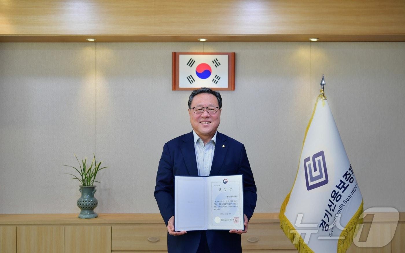 경기신용보증재단이 ‘금융발전 유공 혁신금융부문 금융위원회 위원장 표창’을 받았다. 사진은 시석중 경기신보 이사장이 표창장을 들고 있는 모습.&#40;경기신보 제공&#41;/