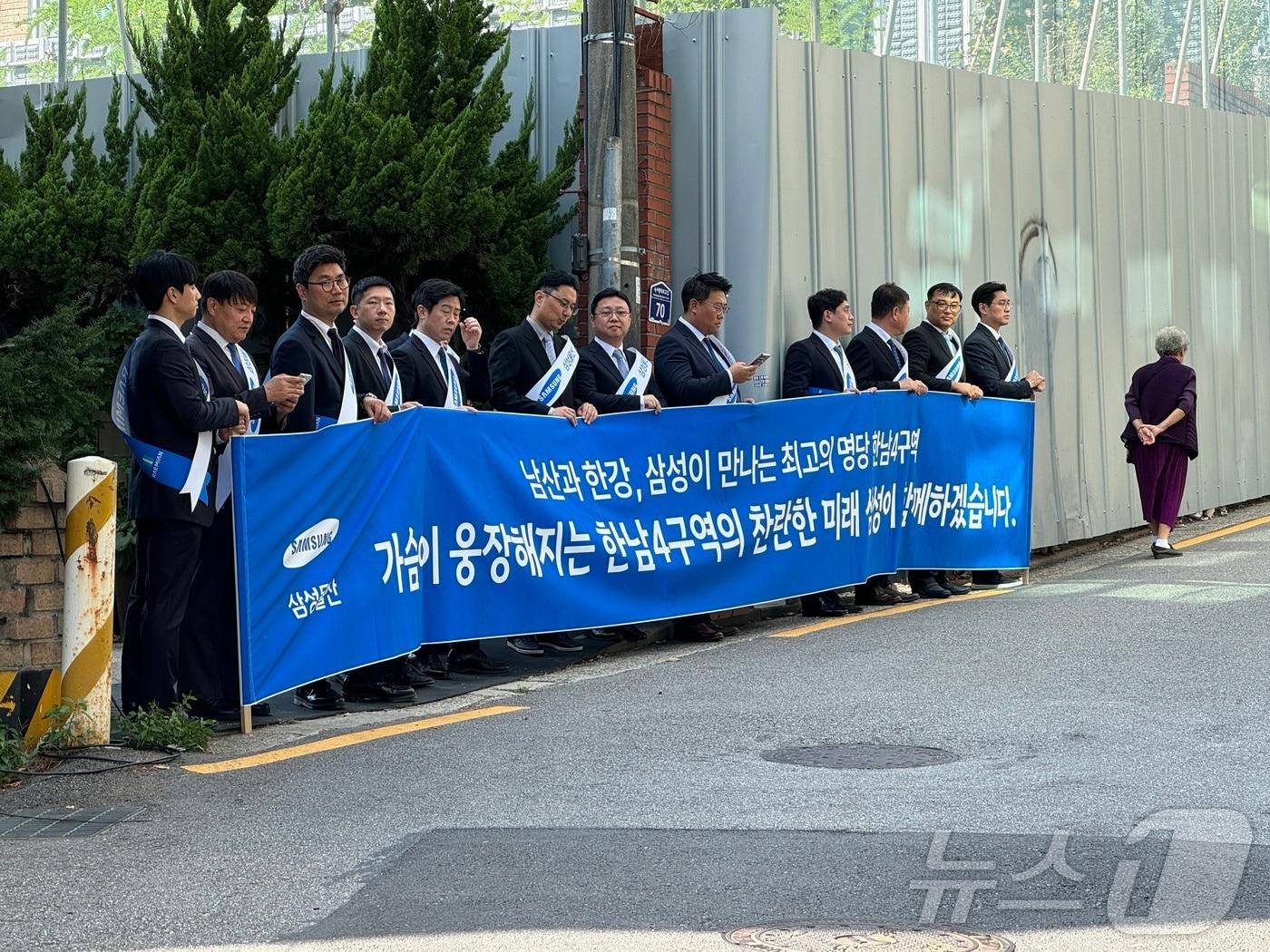 한남4구역 재개발 조합이 이날 용산구 이태원동 조합사무실에서 진행한 시공사 선정 현장설명회에서 삼성물산 직원 십여 명이 플랜카드를 들고 도열해 홍보에 나서고 있다.2024.9.30/뉴스1 ⓒ News1 한지명 기자