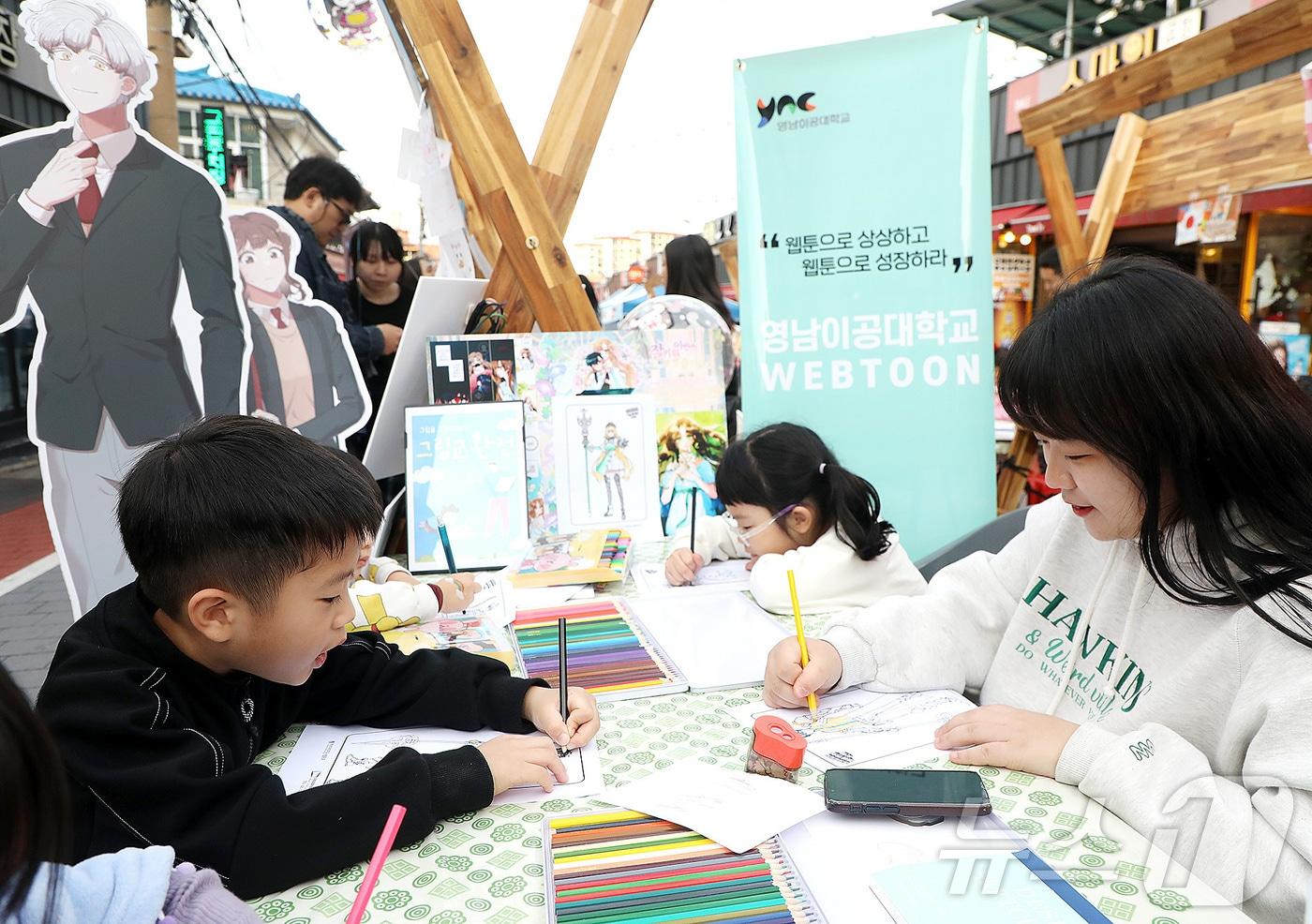 영남이공대 웹툰과 학생들이 9일 &#39;안지랑곱창골목 코스튬 페스티벌&#39; 현장에서 캐릭터 체험 부스를 열고, 어린이들의 웹툰 그리기 체험을 돕고 있다. &#40;영남이공대 제공&#41;