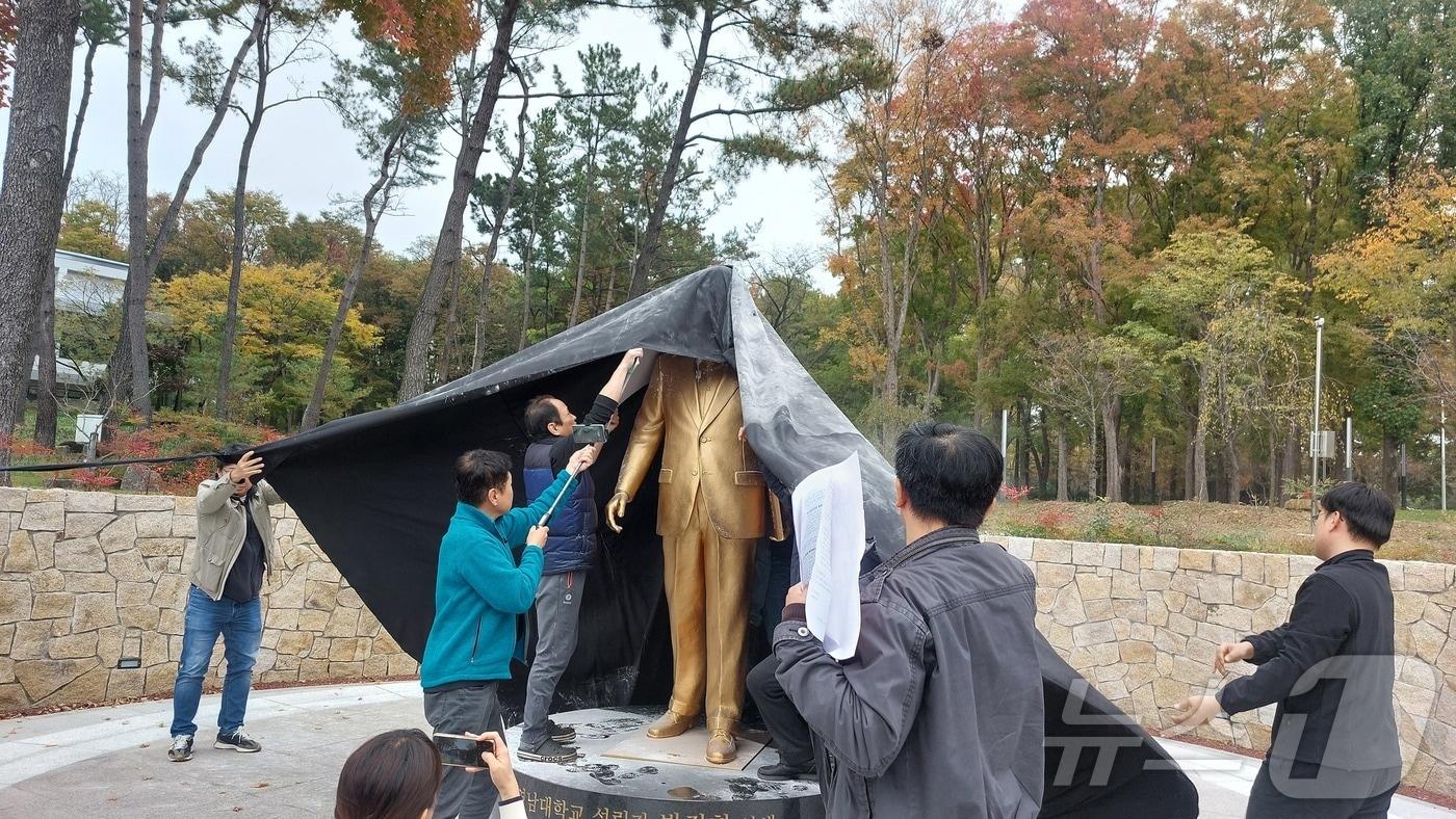 영남대 민주동문회 회원들이 10일 영남대에 건립된 박정희 전 대통령 동상에 달걀과 밀가루를 뿌린 뒤 검은 천을 덮고 있다.&#40;영남대 민주동문회 제공&#41;