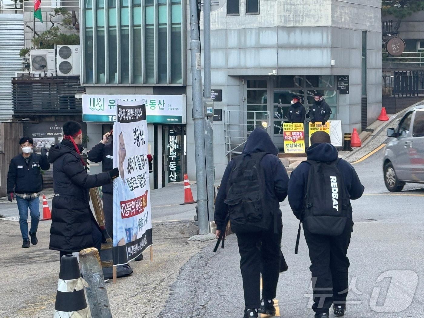 12일  오전 서울 용산구 한남동 정의선 현대차그룹 회장 자택 인근에서 현대트랜시스 노조원들이 현수막과 피켓을 동원한 시위를 벌이는 현장 앞을 주민들이 지나가고 있다. &#40;현대트랜시스 제공&#41;