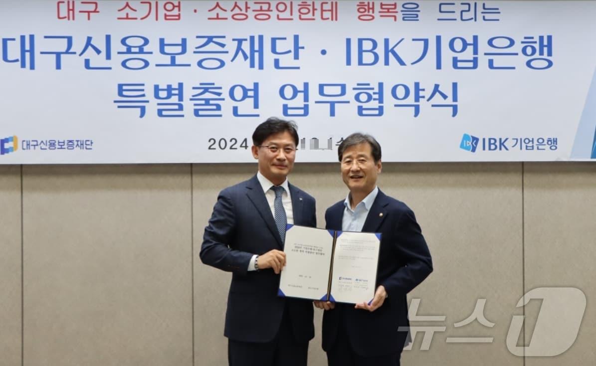 이대홍 IBK기업은행 대구경북동부지역본부장&#40;왼쪽&#41;과 박진우 대구신용보증재단 이사장이 20억 원 특별출연 업무협약을 체결한 후 협약서를 펼쳐 보이고 있다.&#40;대구신보 제공&#41;