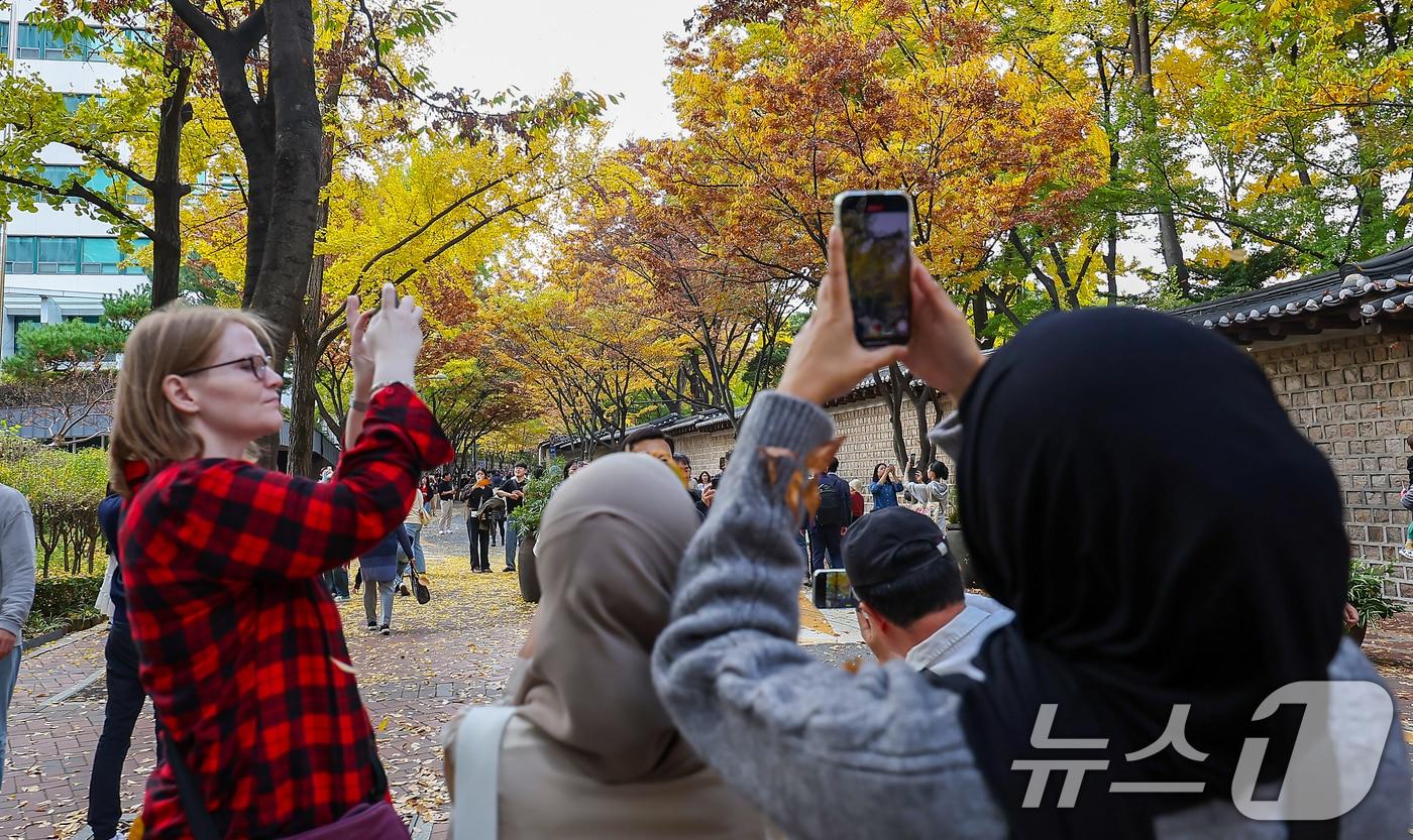 서울의 낮 최고기온이 24도 가까이 오르는 등 포근한 날씨를 보인 3일 오후 서울 중구 덕수궁 돌담길에 단풍이 물든 가운데 외국인 관광객들이 늦가을 정취를 즐기고 있다. 2024.11.3/뉴스1 ⓒ News1 김진환 기자