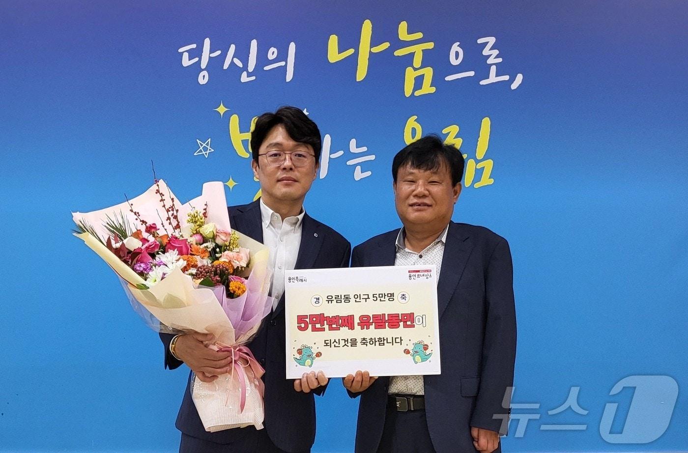 10월28일 처인구 유림동의 5만번째 주민이 된 권병손씨&#40;왼쪽&#41;가 이길재 동장의 축하를 받은 뒤 기념촬영을 하고 있다.&#40;용인시 제공&#41;