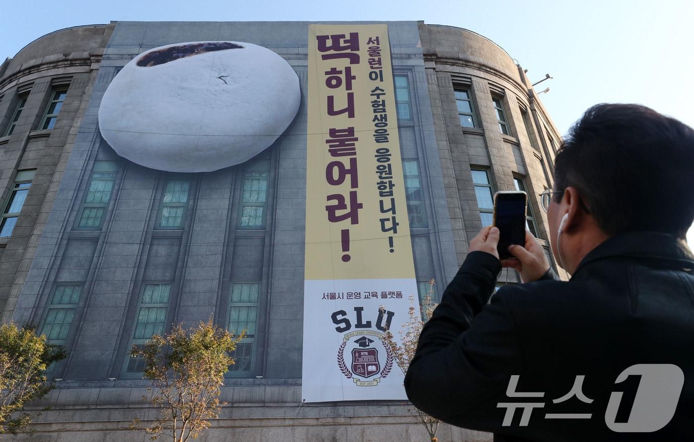 한 시민이 서울도서관 외벽에 걸린 수험생을 응원하는 대형 현수막 사진을 찍고 있다. /뉴스1 ⓒ News1 박세연 기자