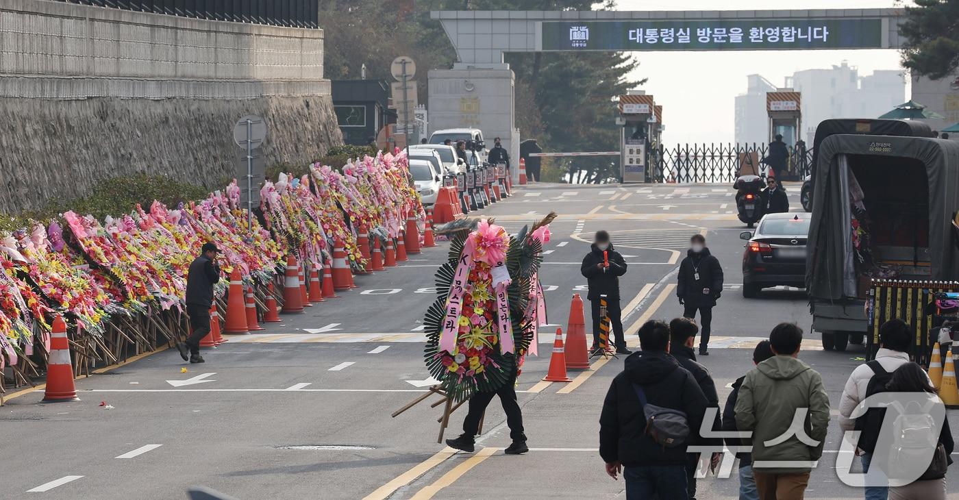 11일 오후 서울 용산구 대통령실 출입문 앞 도로에서 화환 업체 관계자가 윤석열 대통령 지지자들이 보낸 화환을 옮기고 있다. 2024.12.11/뉴스1 ⓒ News1 장수영 기자