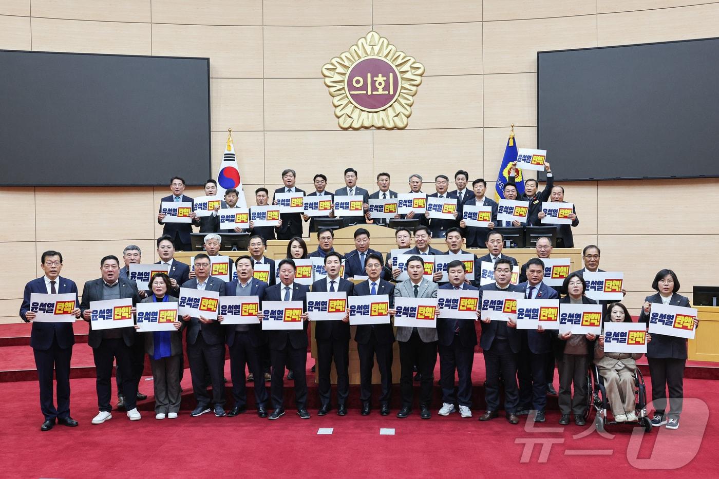 전남도의회가 12일 윤석열 대통령 대국민 담화 직후 체포와 탄핵을 촉구하는 결의안을 가결하고 손팻말을 들고 있다.&#40;전남도의회 제공&#41;2024.12.12./뉴스1