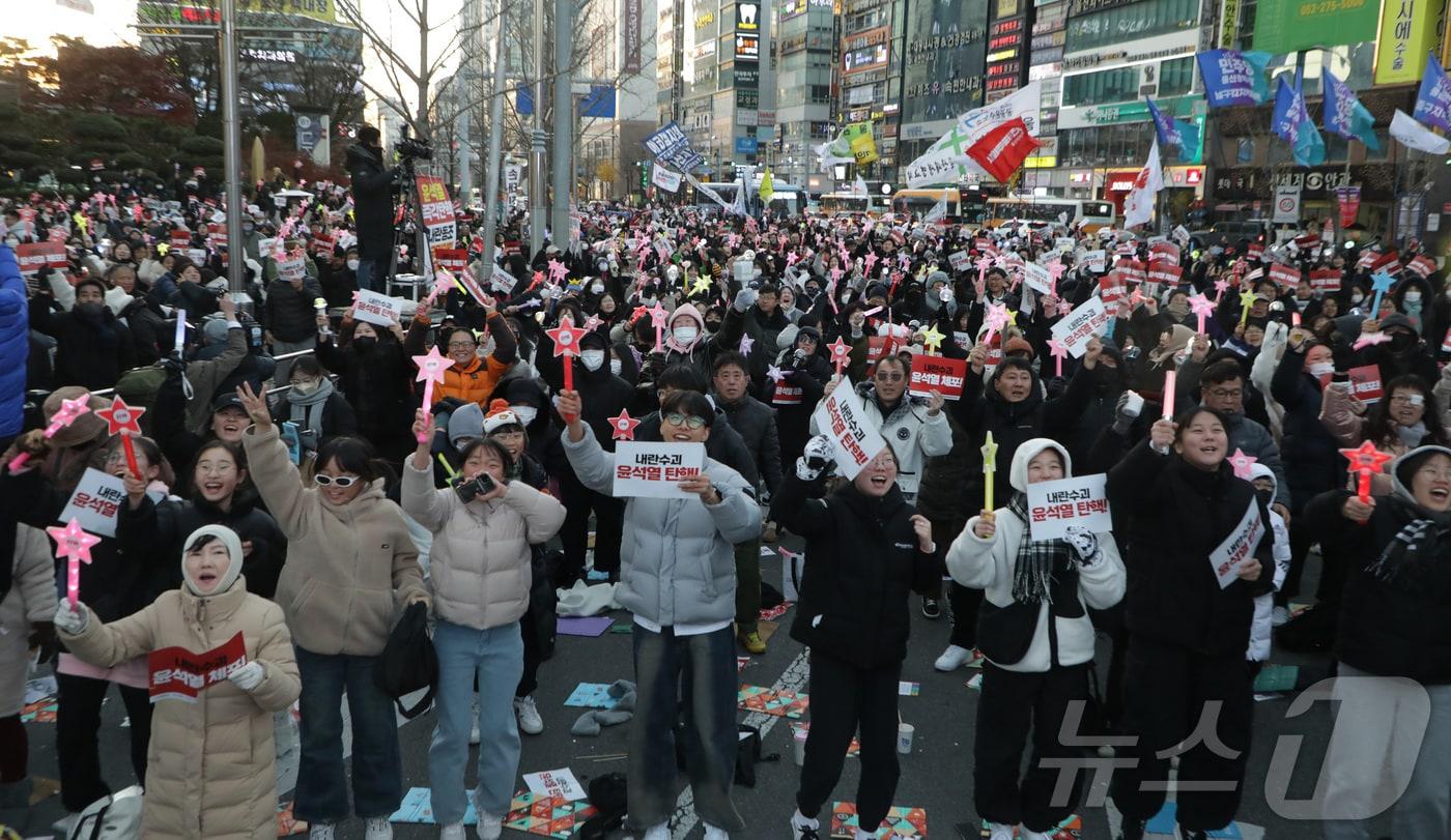 윤석열 대통령의 2차 탄핵소추안이 가결된 14일 오후, 울산 남구 롯데백화점 앞에서 이를 지켜보던 시민들이 자리에서 일어나 기뻐하고 있다.2024.12.14/뉴스1 ⓒ News1 김지혜 기자