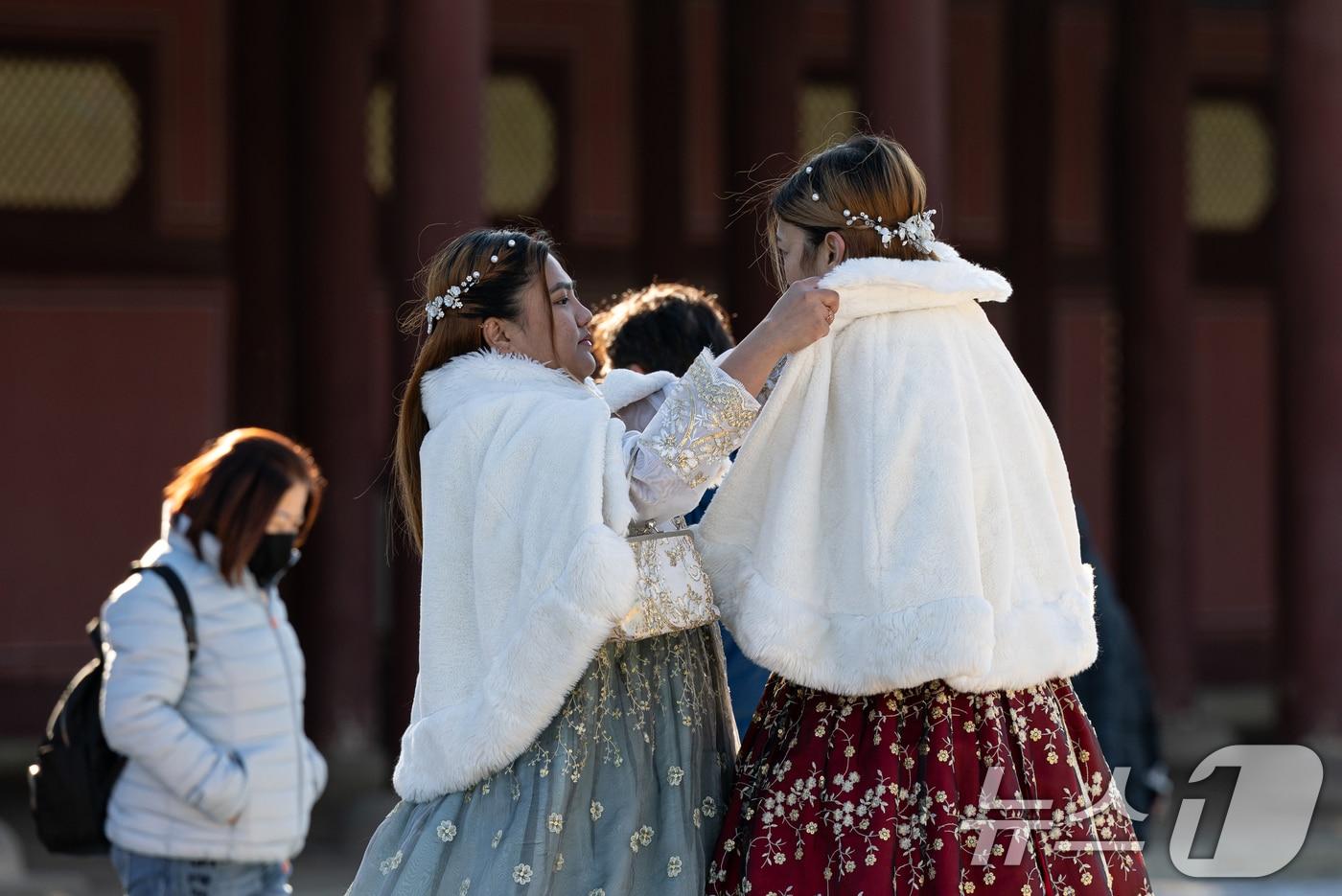 아침 기온이 떨어지며 추운 날씨를 보인 22일 오후 서울 종로구 경복궁을 찾은 외국인 관람객이 서로 외투를 고쳐 입혀주고 있다. 2024.12.22/뉴스1 ⓒ News1 이승배 기자