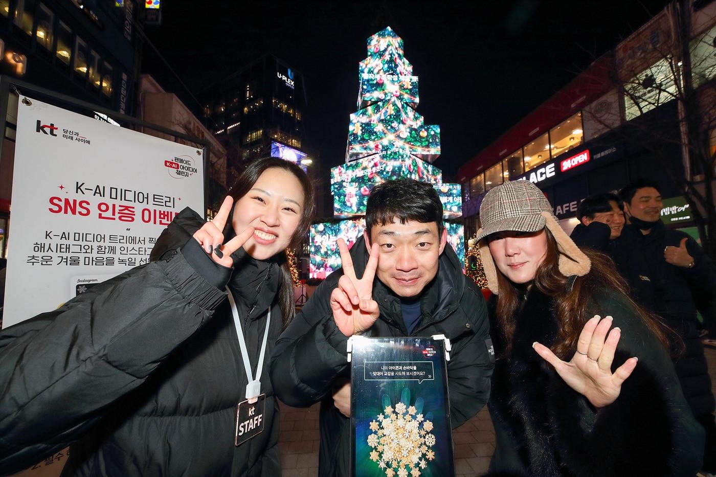 고객들이 서울 서대문구 신촌 거리에 설치된 KT &#39;팬메이드 K-AI아이디어 챌린지&#39; 팝업 미디어 트리 앞에서 기념 촬영을 하고 있는 모습&#40;KT 제공&#41;