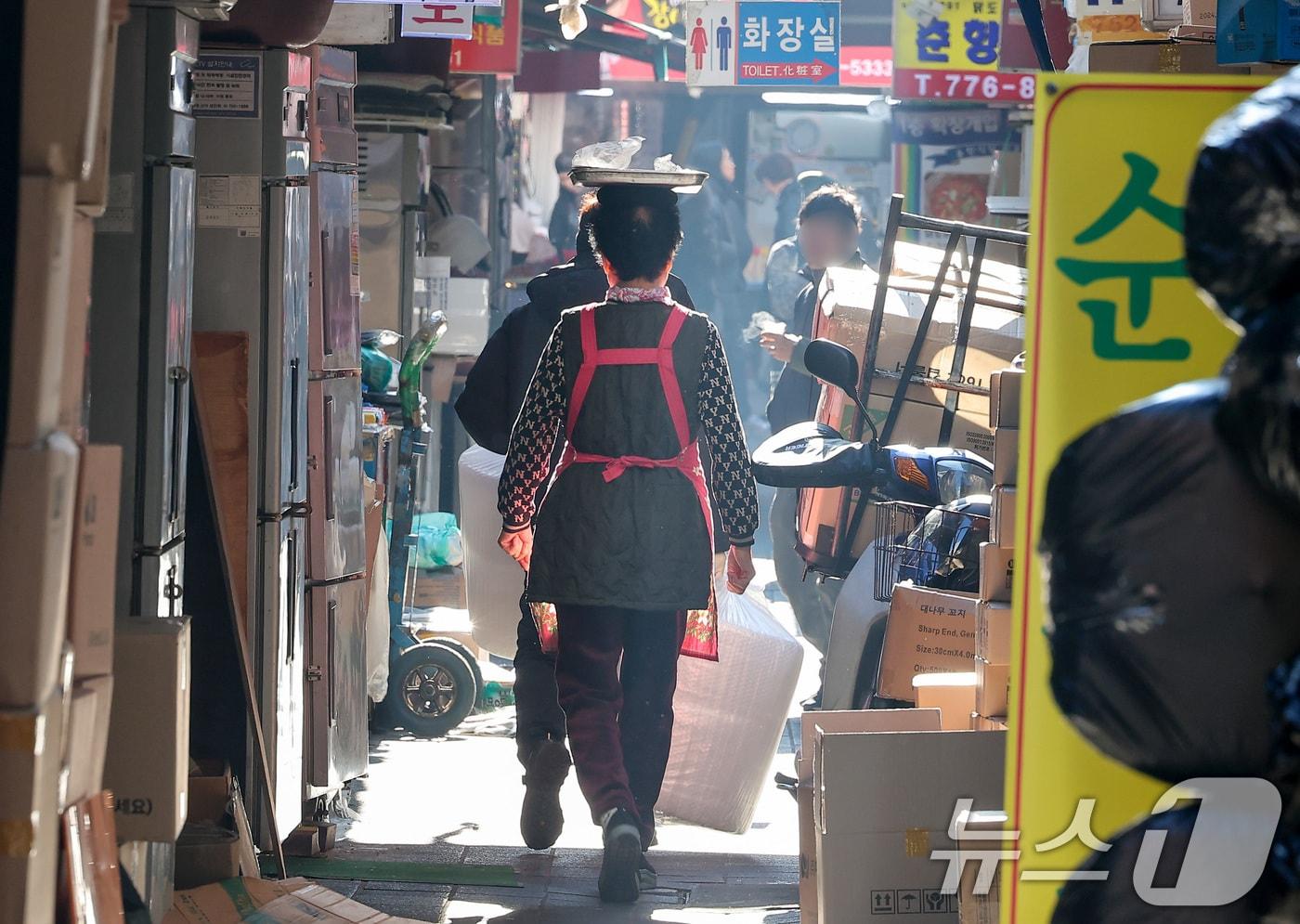 사진은 이날 서울 남대문 시장에서 한 상인이 점심 메뉴를 머리에 이고 배달하고 있다. 2024.12.23/뉴스1 ⓒ News1 김성진 기자