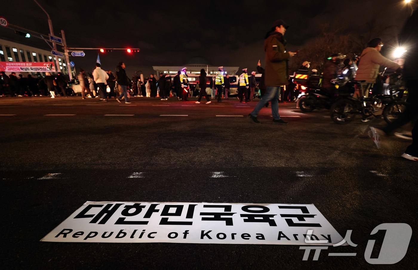 윤석열 대통령이 비상계엄령을 선포한 가운데 4일 새벽 서울 여의도 국회 앞에 육군 버스에 붙어 있는 현판이 떨어져 있다. 2024.12.4/뉴스1 ⓒ News1 구윤성 기자