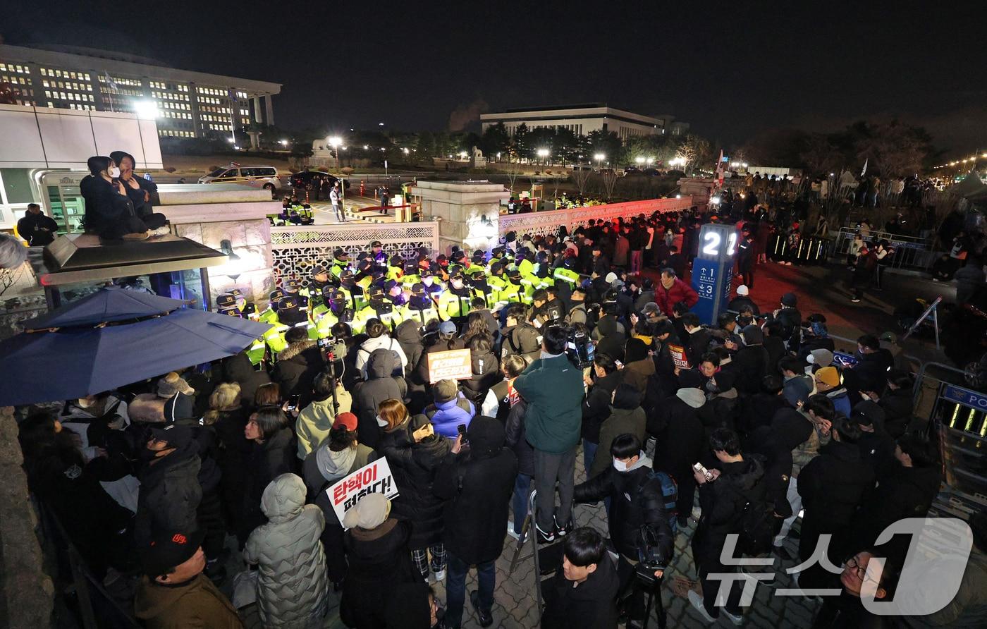 윤석열 대통령의 비상계엄 해제 요구 결의안이 국회 본회의에서 통과된 4일 새벽 서울 여의도 국회 정문 앞에 모인 시민들이 윤 대통령을 규탄하고 있다. 여야는 이날 본회의에서 재석 190명 중 찬성 190명으로 비상계엄 해제 요구 결의안을 가결 처리했다. 이에 따라 계엄령 선포는 무효가 됐다고 국회의장실은 설명했다. 2024.12.4/뉴스1 ⓒ News1 장수영 기자