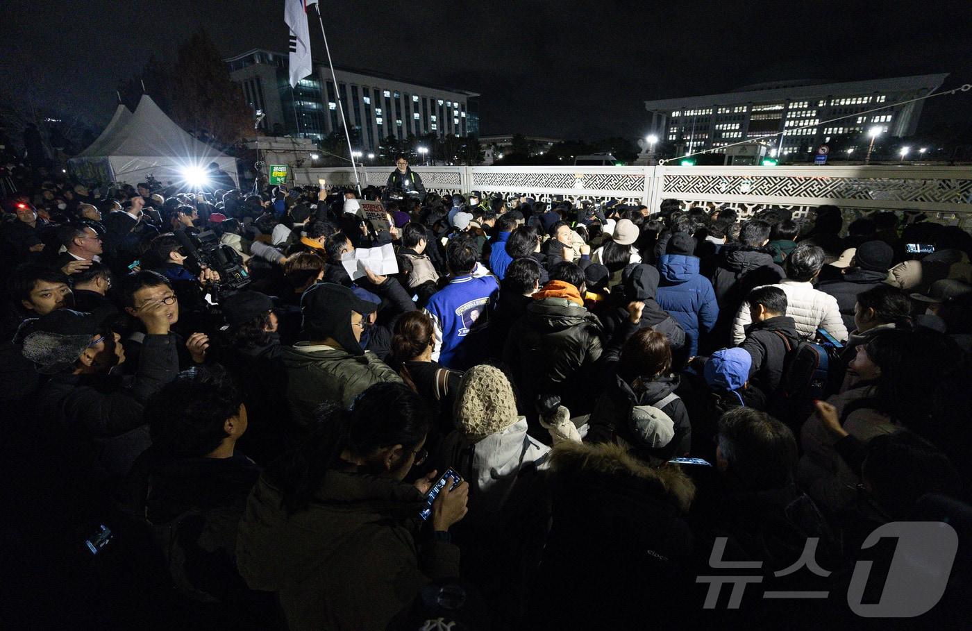 윤석열 대통령의 비상계엄 해제 요구 결의안이 국회 본회의에서 통과된 4일 새벽 서울 여의도 국회 정문 앞에 모인 시민들이 모여 있다. 여야는 이날 본회의에서 재석 190명 중 찬성 190명으로 비상계엄 해제 요구 결의안을 가결 처리했다. 이에 따라 계엄령 선포는 무효가 됐다고 국회의장실은 설명했다. 2024.12.4/뉴스1 ⓒ News1 이재명 기자